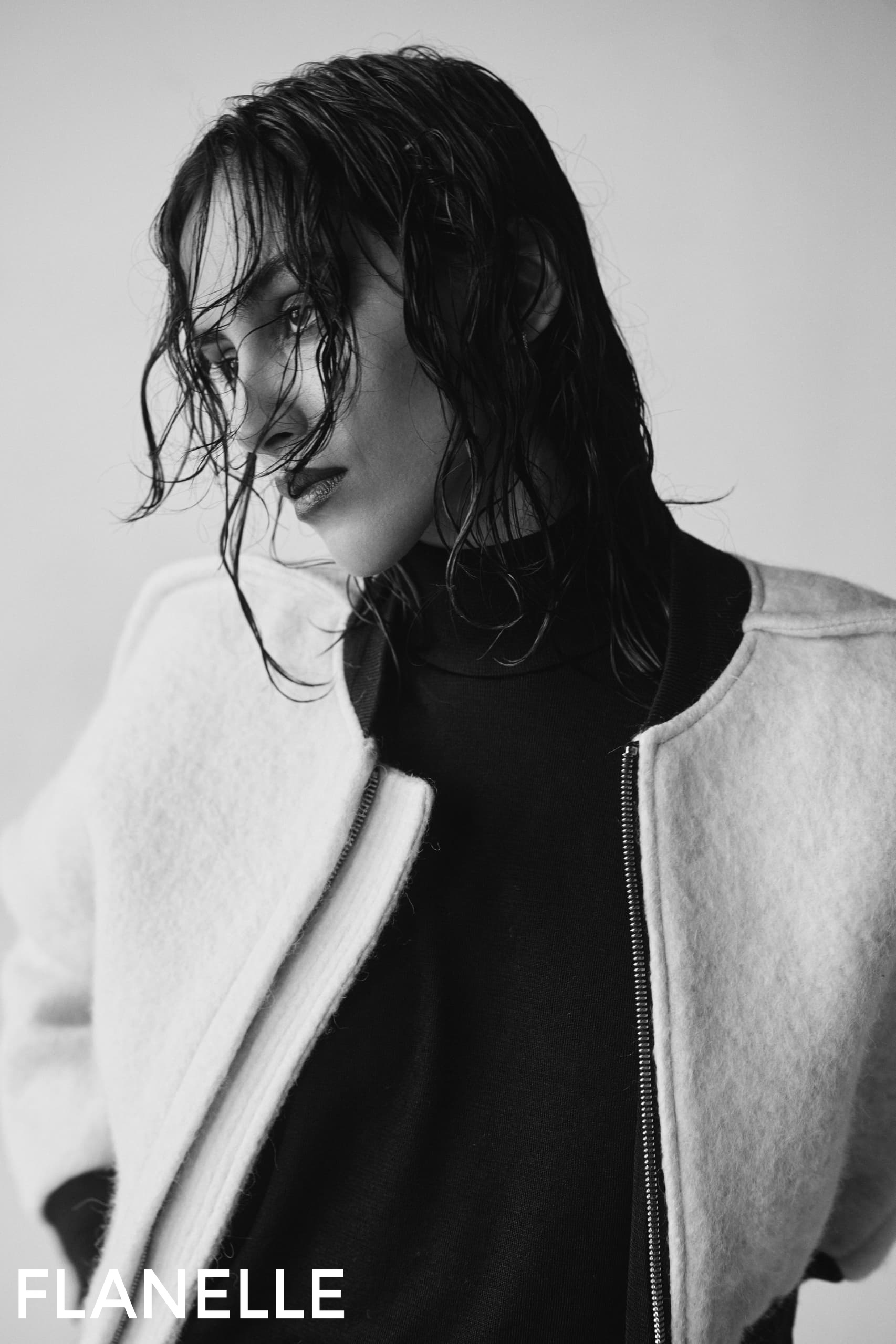 Moody black-and-white portrait of a person with wet hair wearing a stylish jacket.