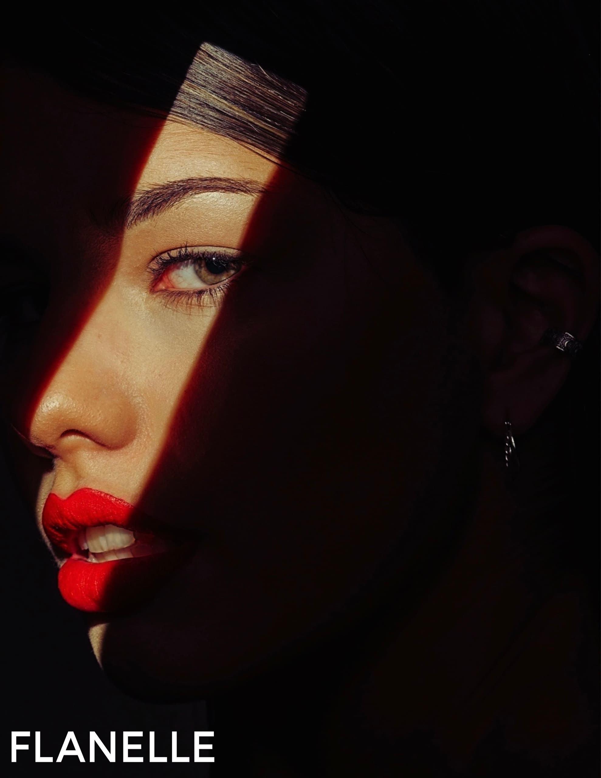 Model with shadow and red lips, dramatic lighting. Flanelle magazine cover.