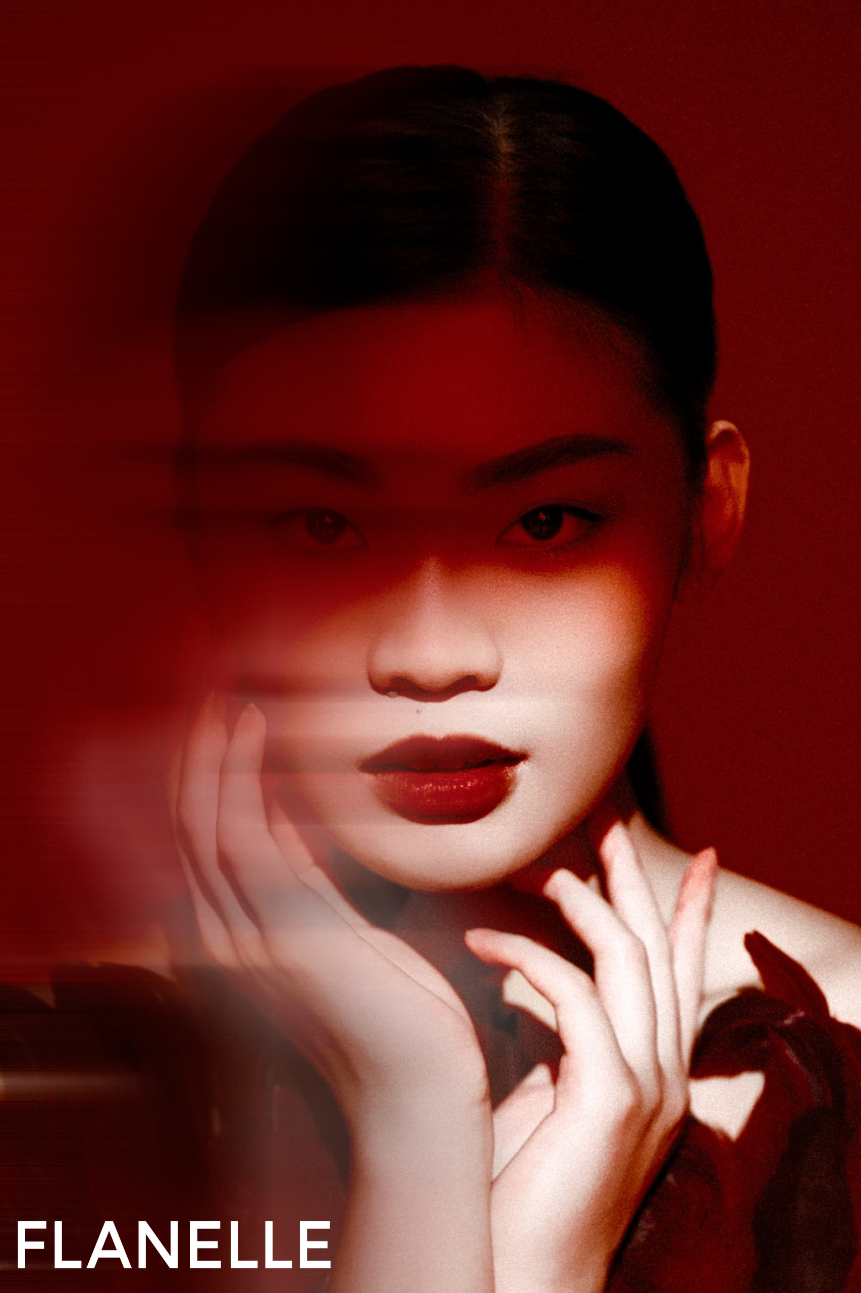 Mystical woman with bold red lips framed by hands in dramatic lighting.