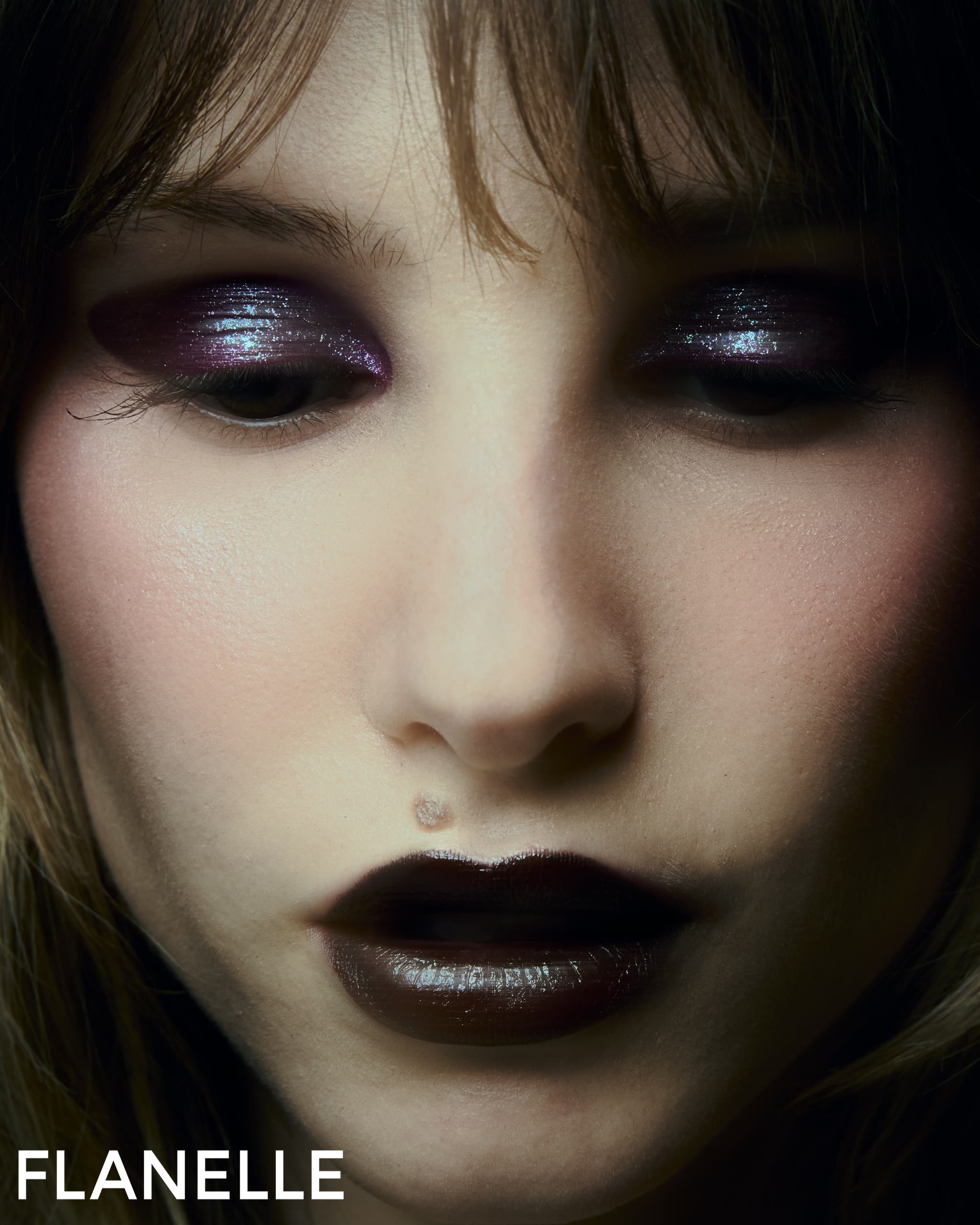 Close-up of a model with bold makeup and dark lipstick, Flanelle branding.