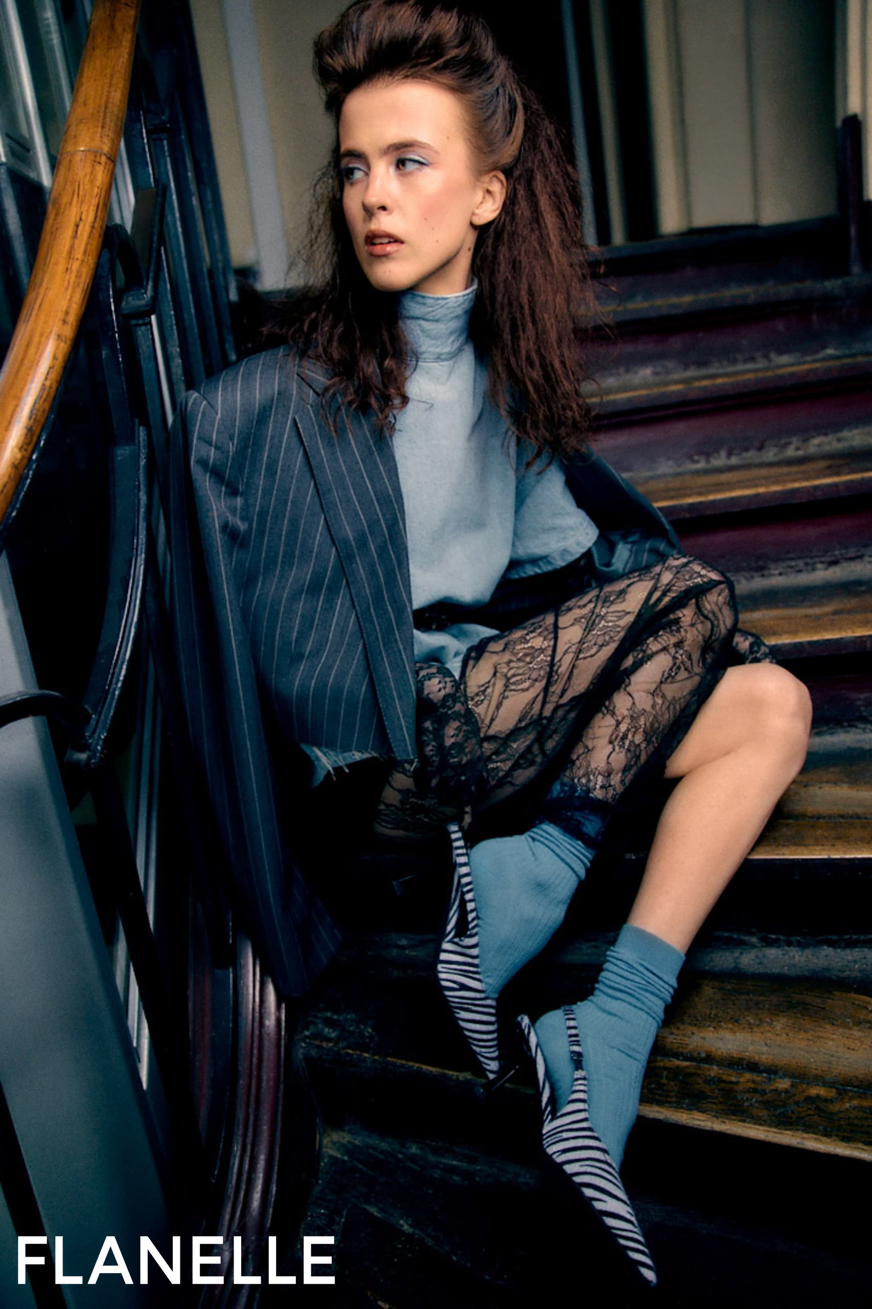 Fashion model in stylish outfit sitting on stairs, trendy blazer and lace skirt.