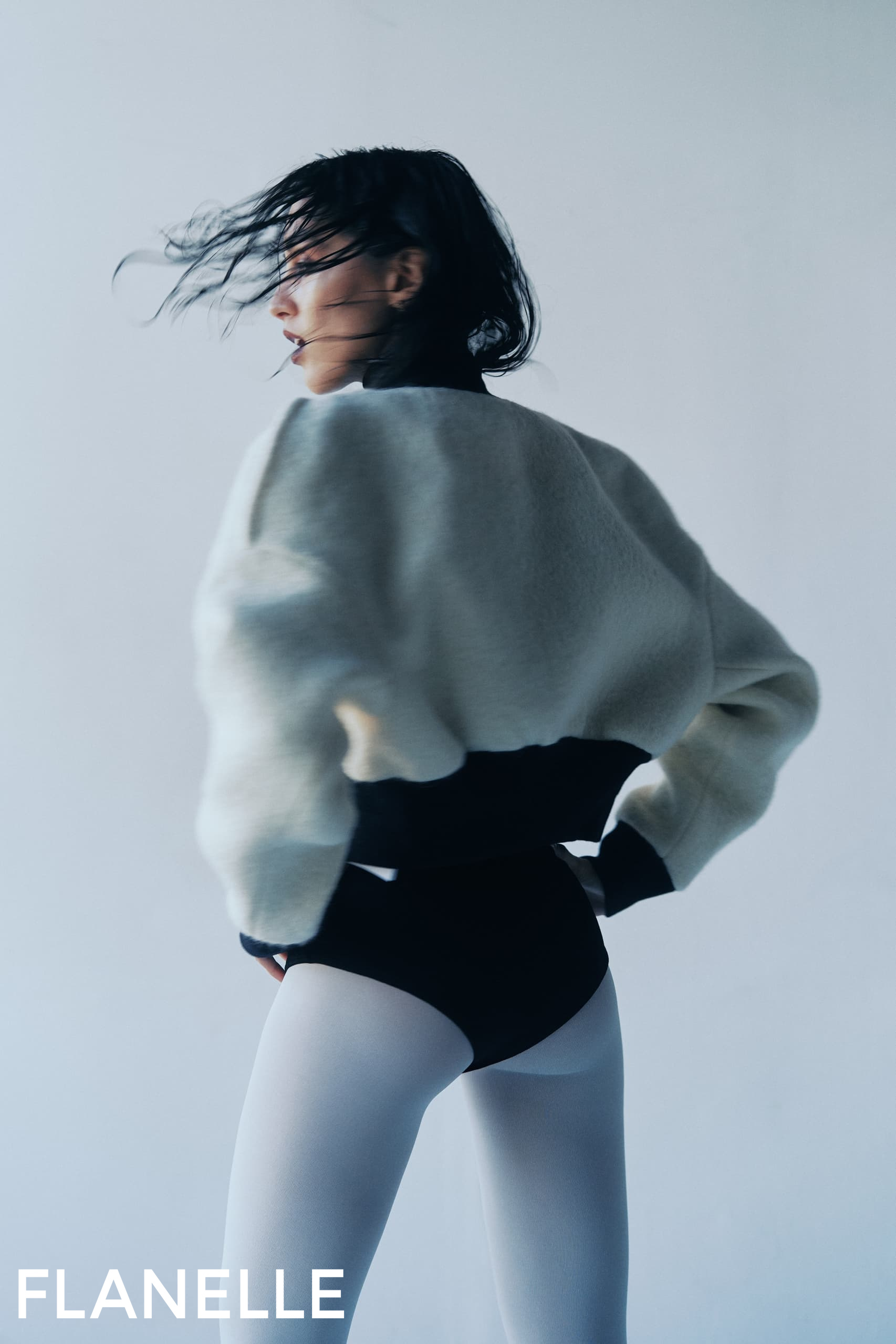 Fashion model in dynamic pose wearing stylish attire.