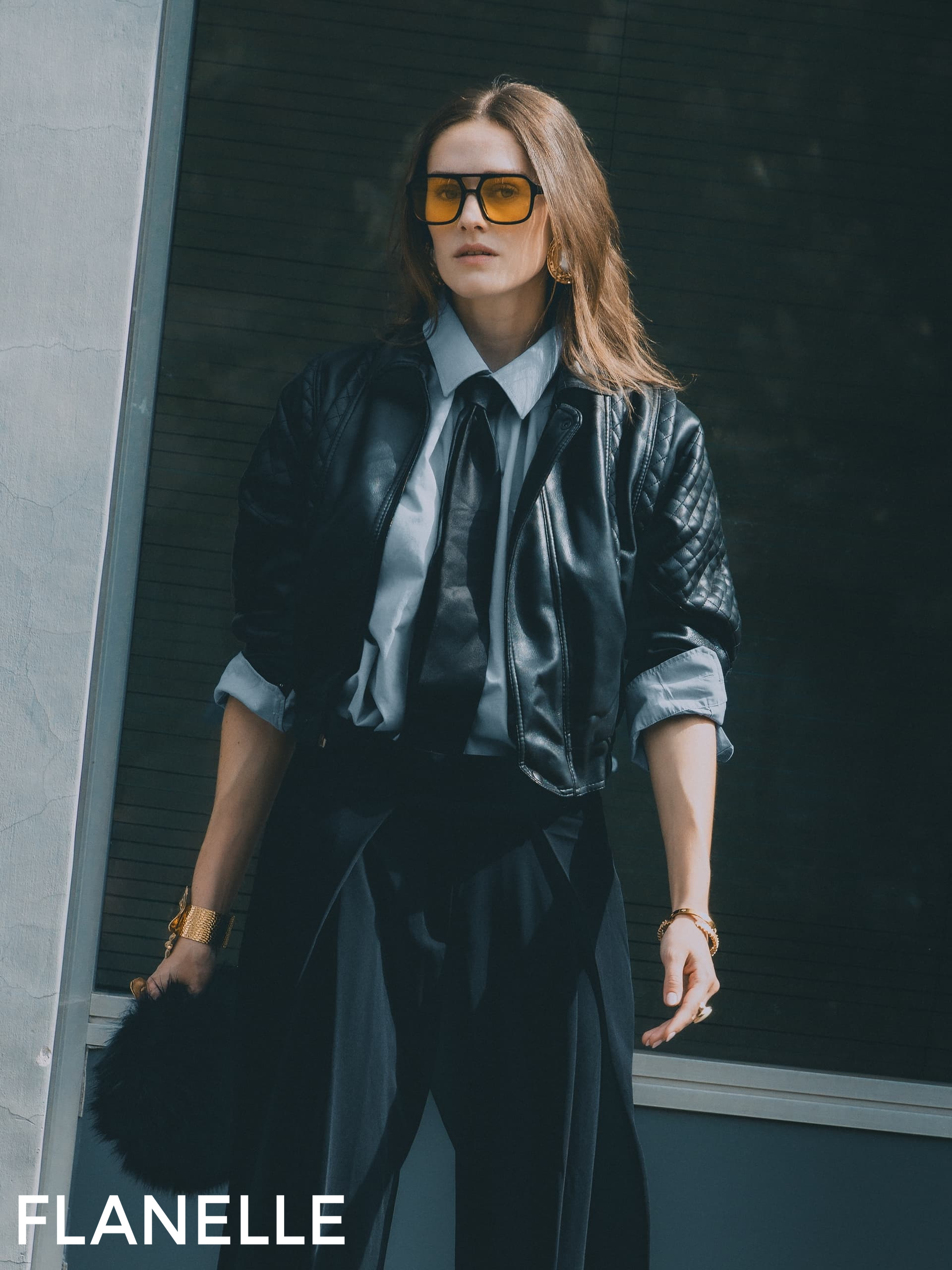 Stylish woman in leather jacket and sunglasses outdoors.