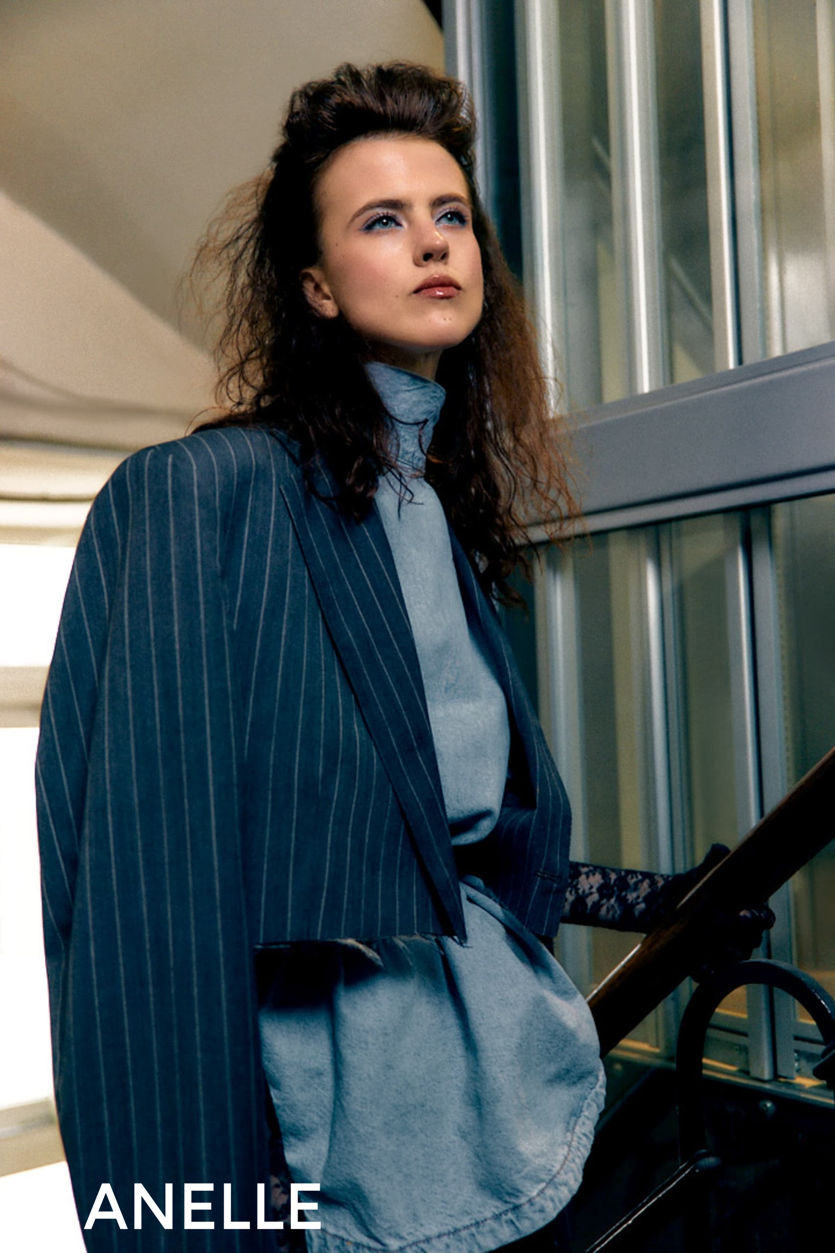 Model in elegant pinstripe suit on stairs, stylish fashion photoshoot.