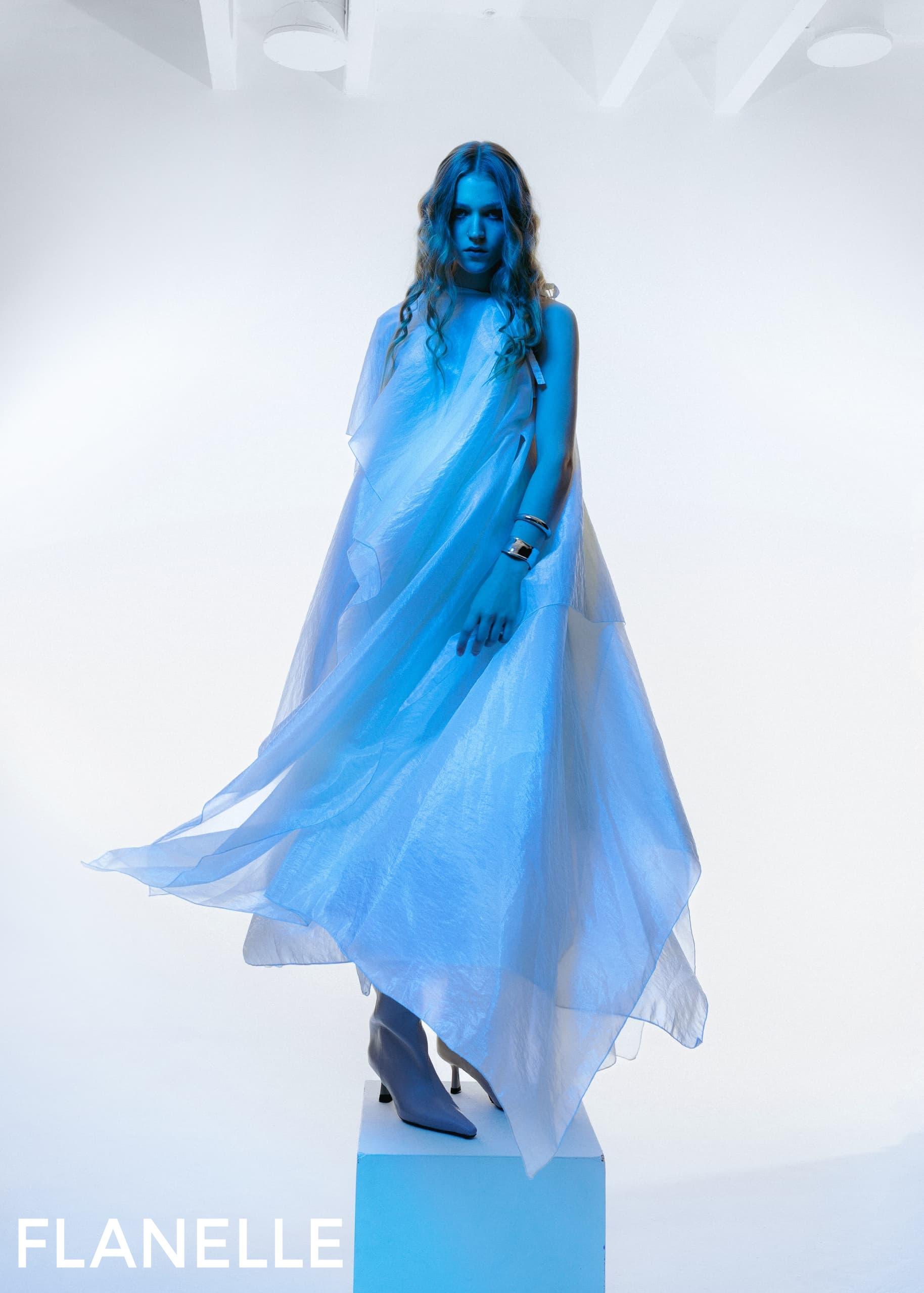 Model in flowing blue dress and boots by Flanelle, studio fashion shoot.