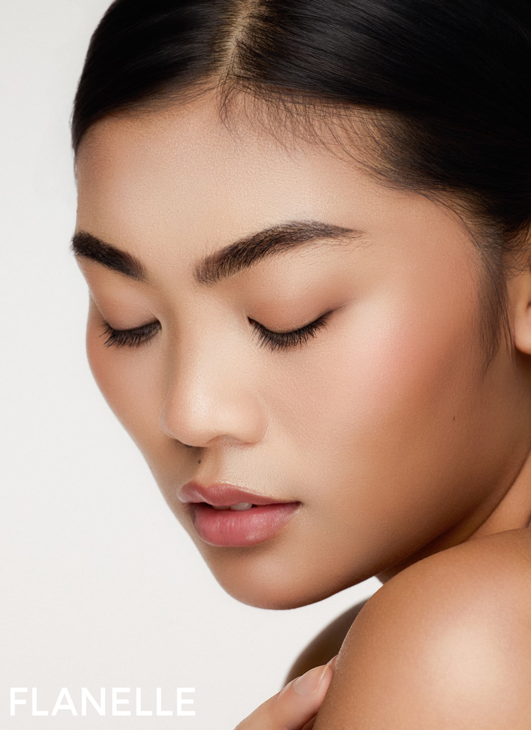 Close-up of a serene woman with flawless makeup and closed eyes.