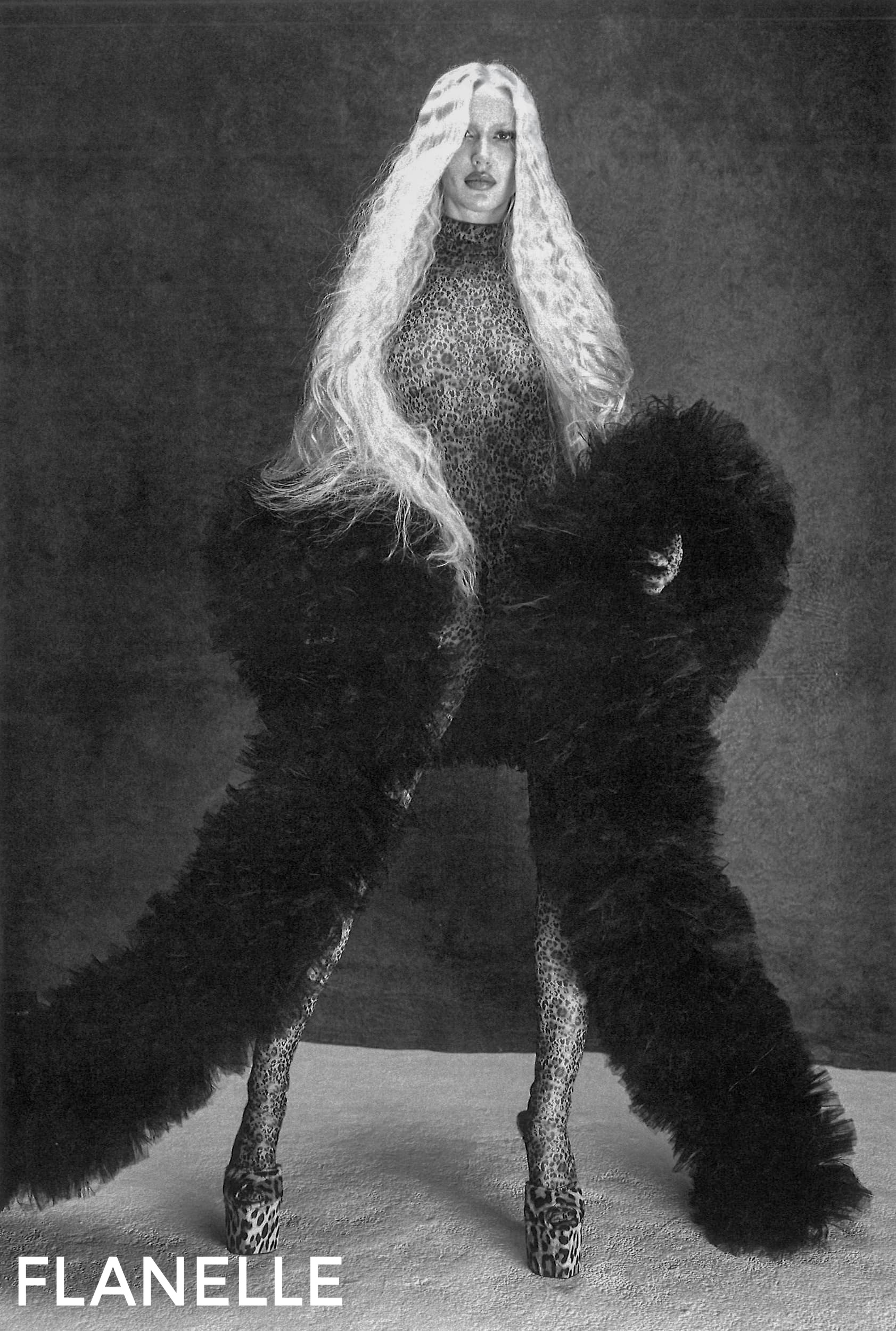 Fashion model in leopard print outfit with long blonde hair and fur accents.