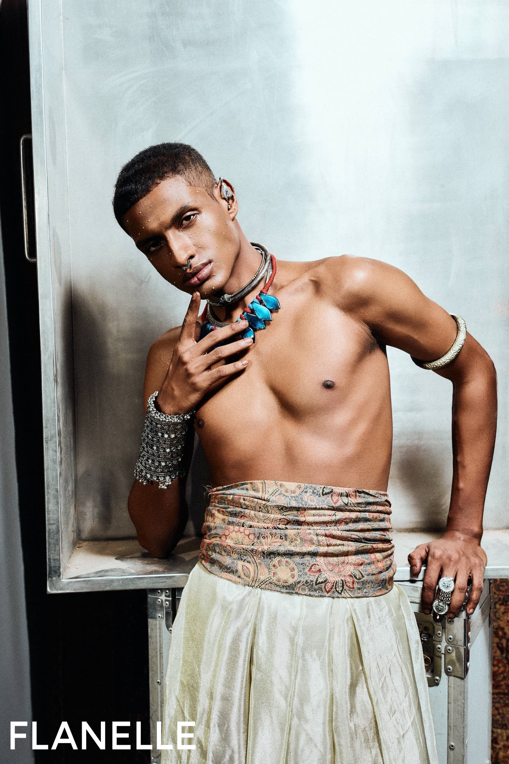 Fashion model poses in eclectic jewelry and patterned wrap skirt.