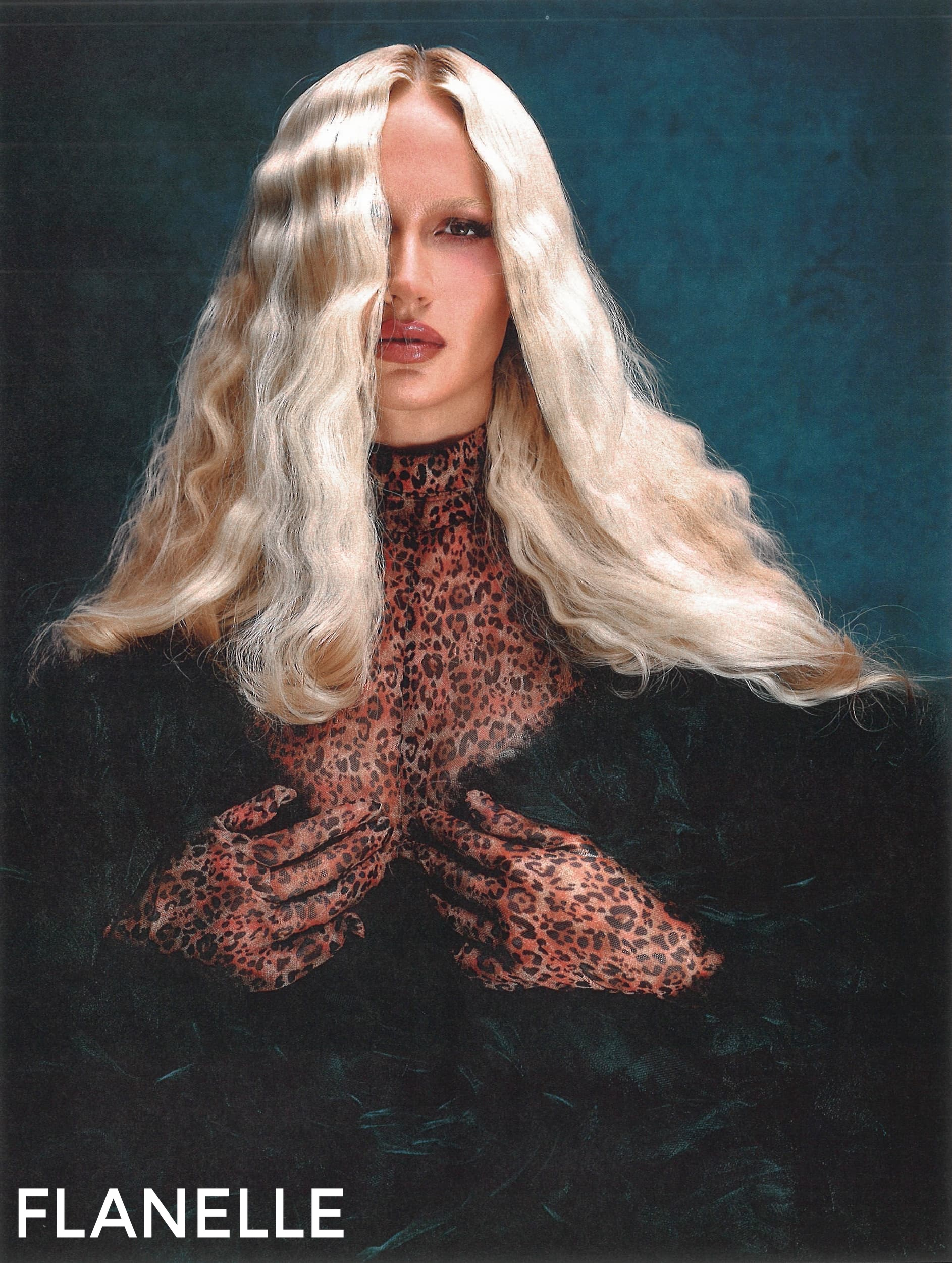 Person with long blonde hair and leopard print top against a blue background.