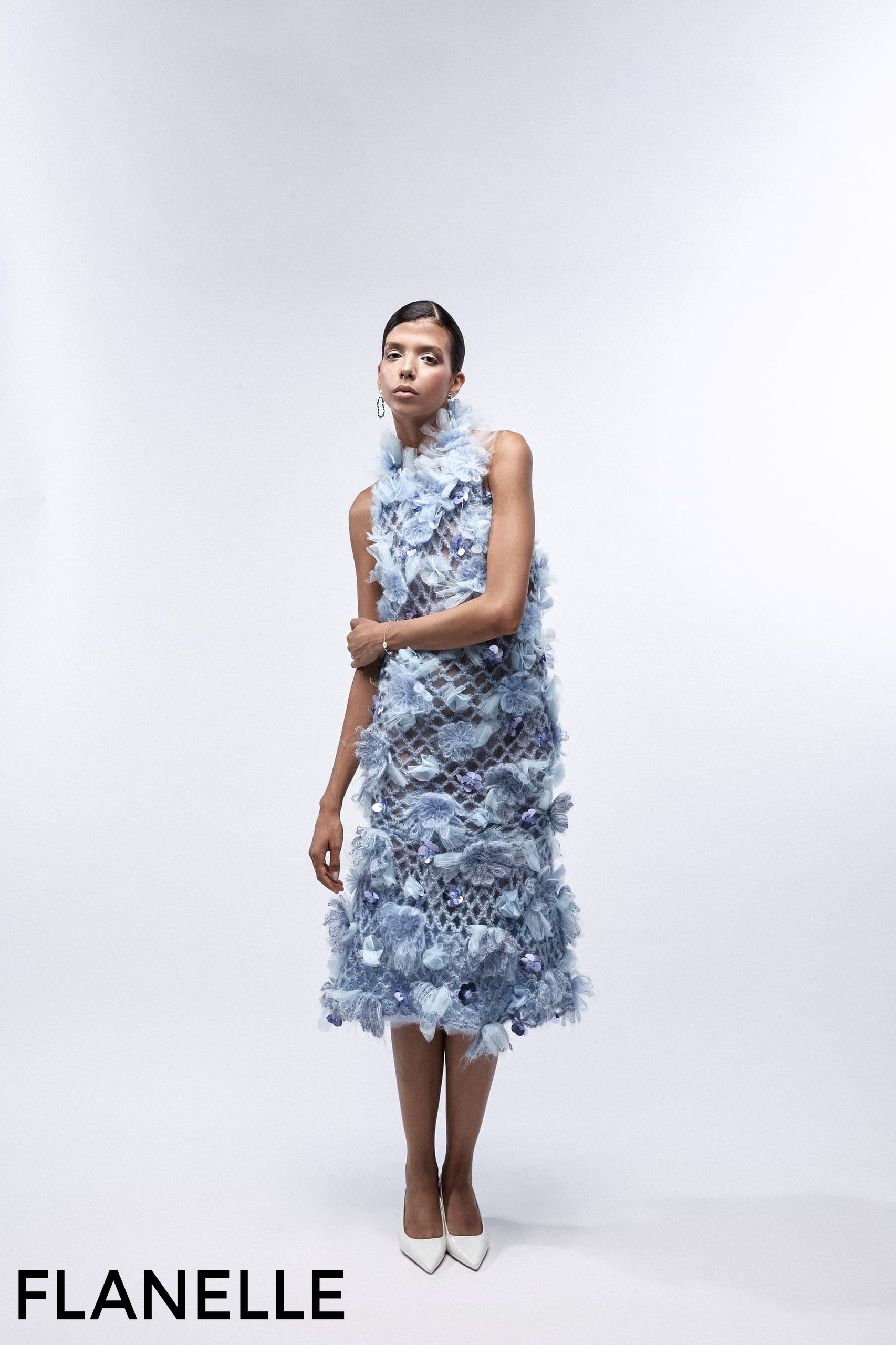 Model in a textured blue dress, high-fashion editorial shoot.