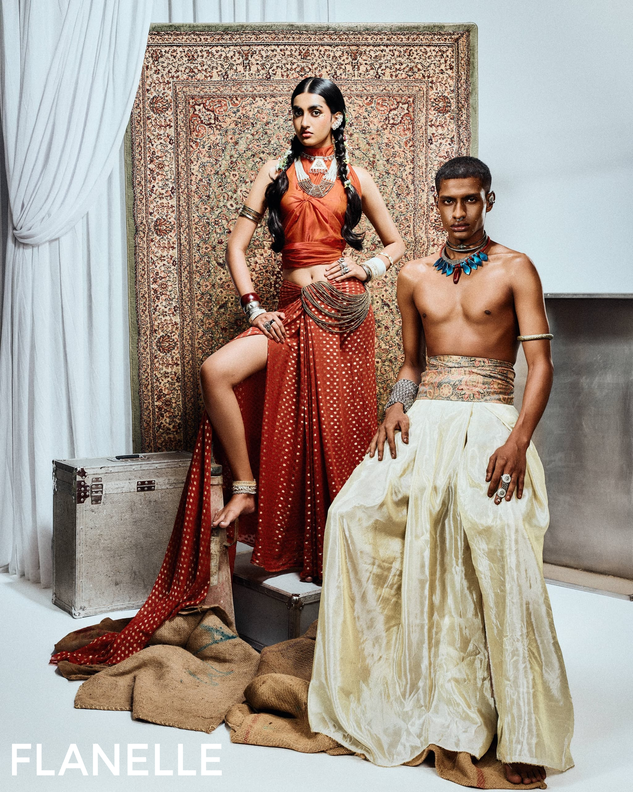 Two models in vibrant, traditional attire against a patterned backdrop.