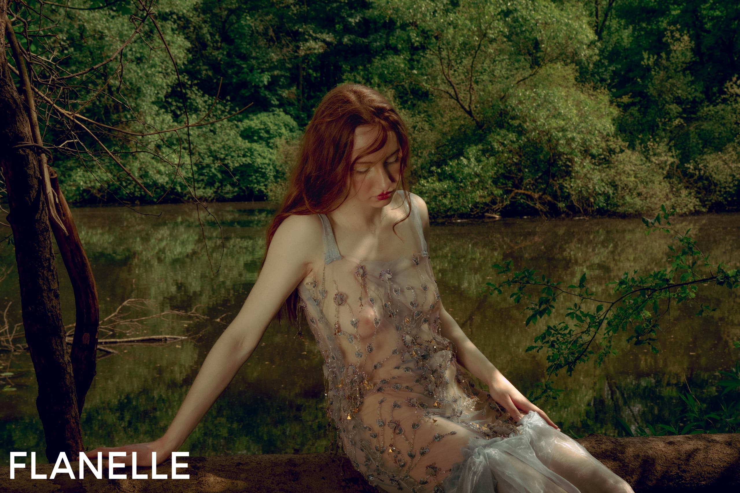 Woman in a delicate dress by a serene forest pond.