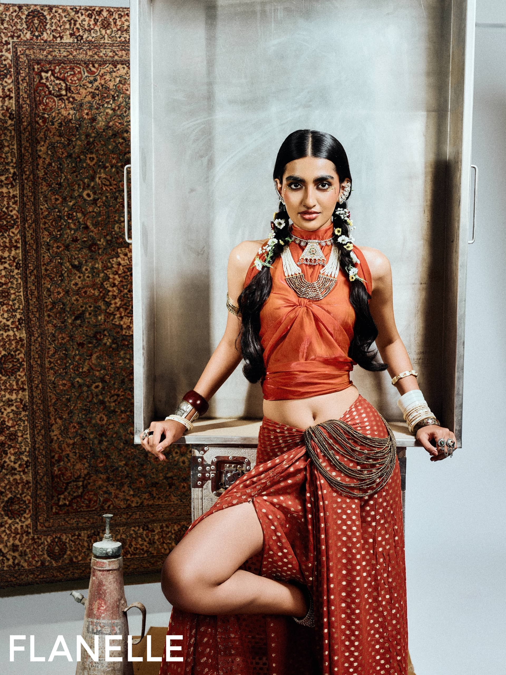 Fashionable woman in traditional Indian attire with jewelry, striking pose in studio.
