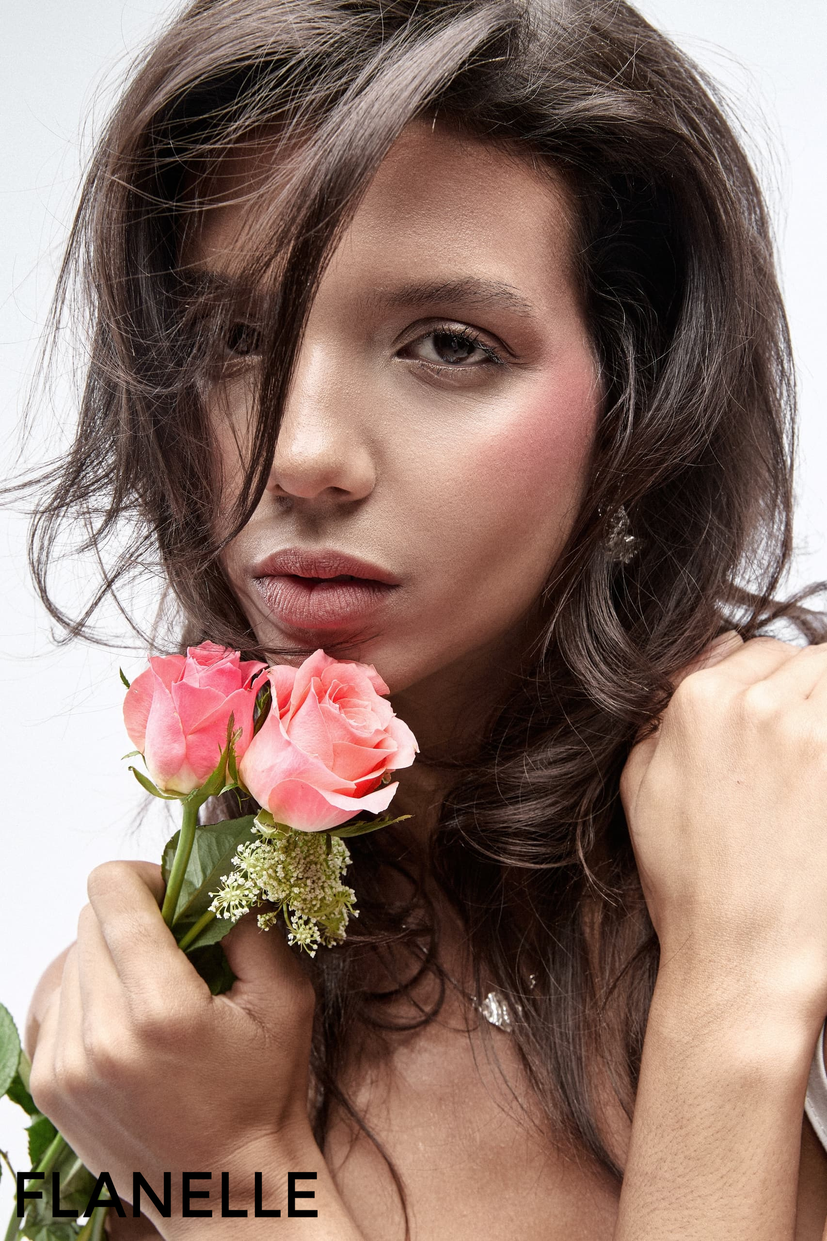 Woman holding pink roses, expressive gaze, natural beauty.