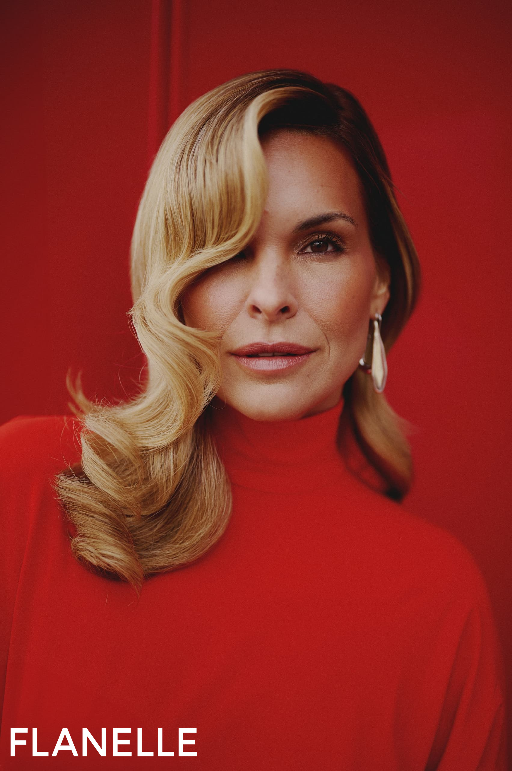 Blonde woman in red turtleneck with waves, bold background, Flanelle magazine shoot.