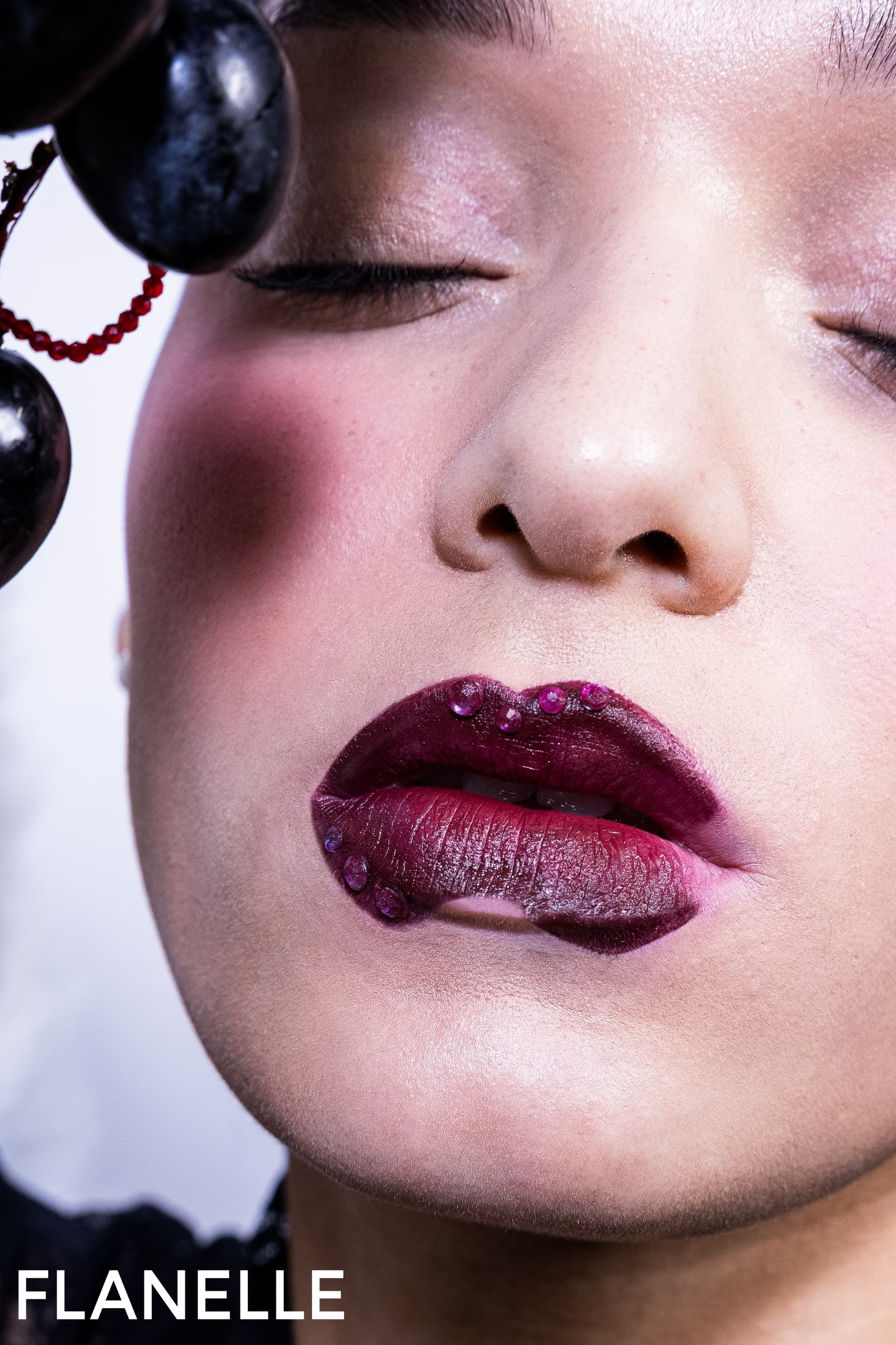 Close-up of artistic makeup with dark berry lips and glossy finish.