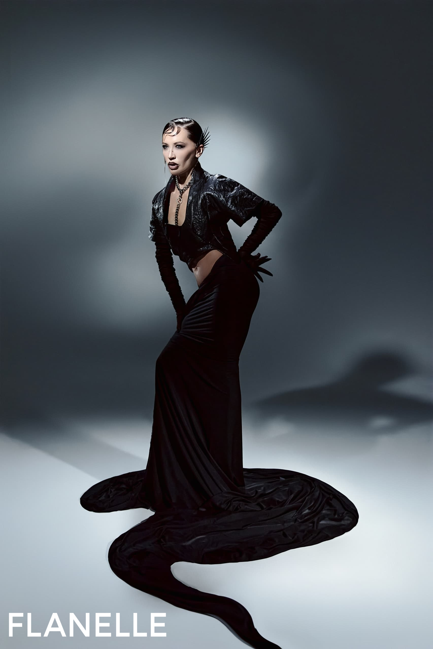 Fashion model in dramatic black gown on a studio backdrop.