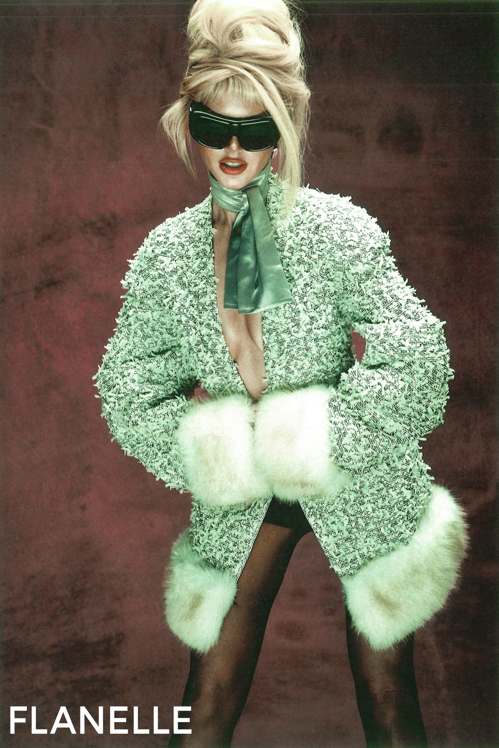 Fashion model in stylish green coat with fur cuffs and large sunglasses.