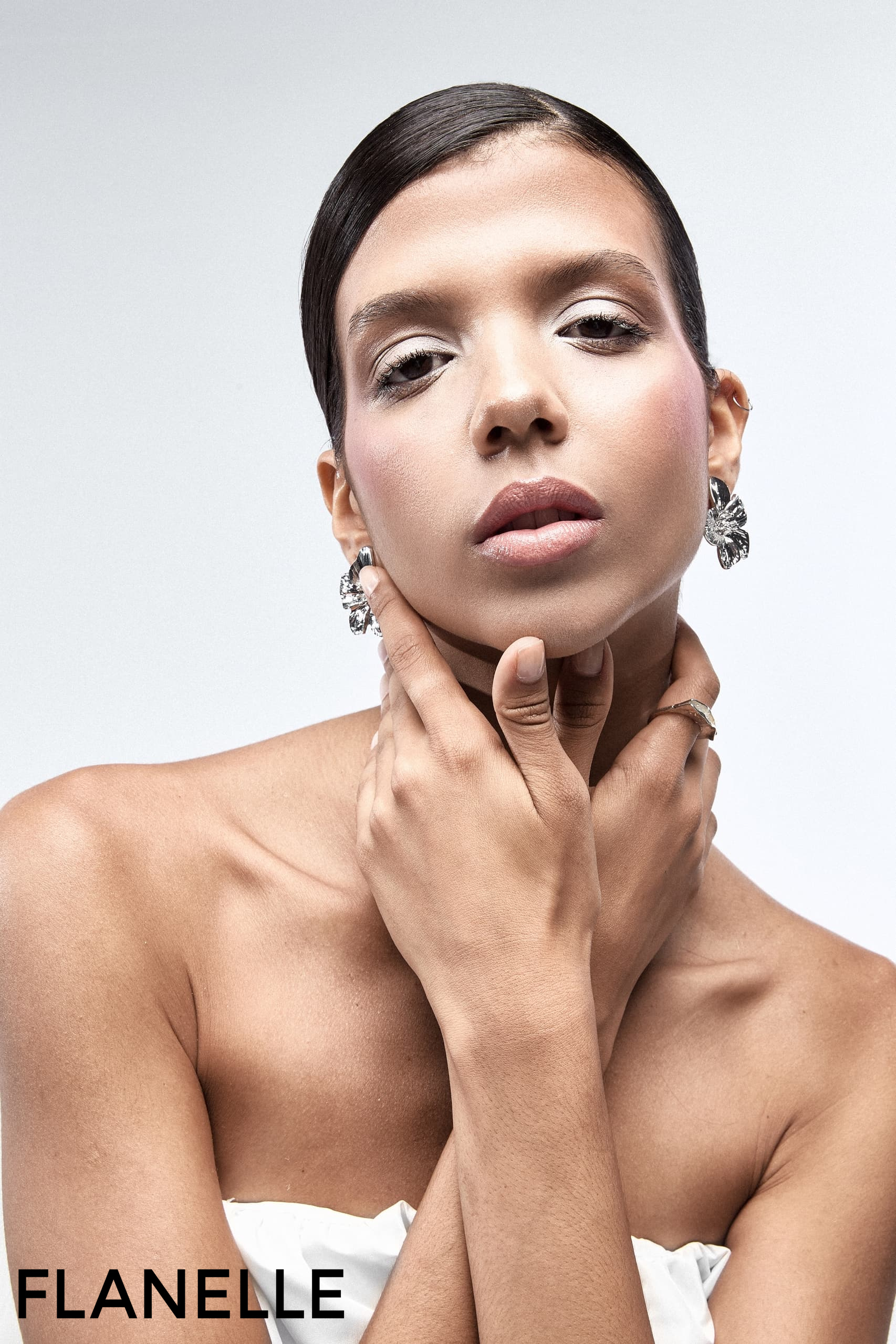 Fashion model in elegant pose wearing statement earrings, photographed by Flanelle.