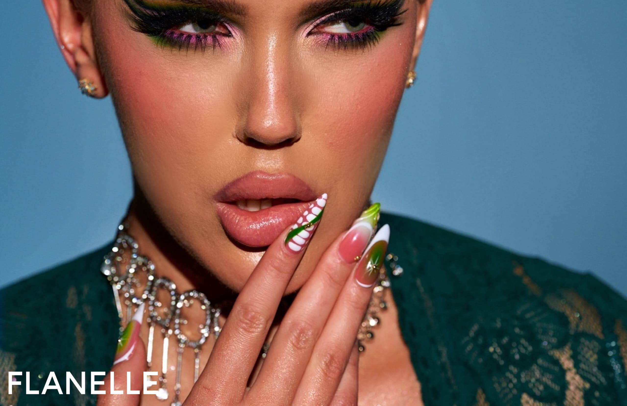 Model showcasing vibrant nail art and bold makeup with intricate accessories.