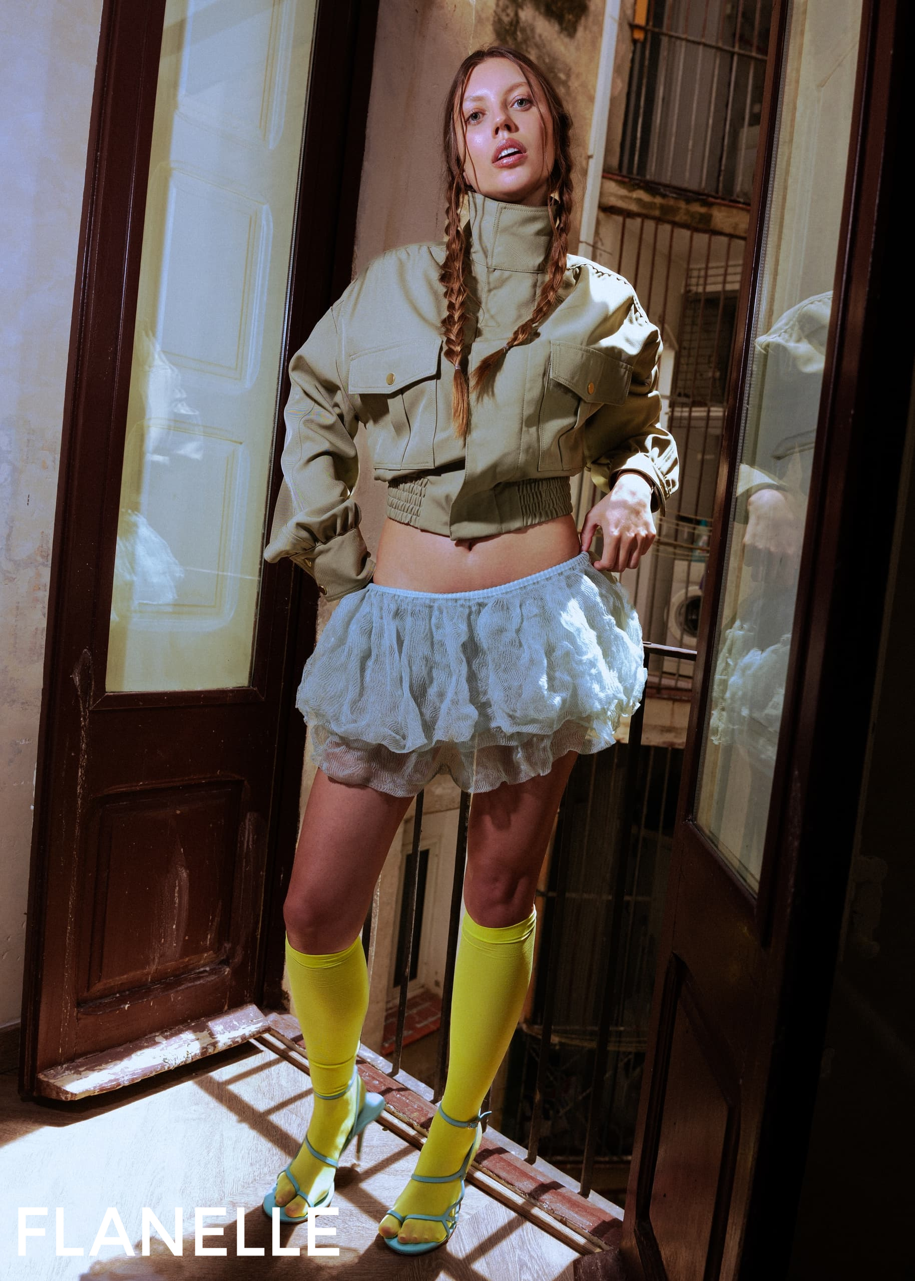 Trendy fashion model in stylish outfit with braided hair and yellow high socks.