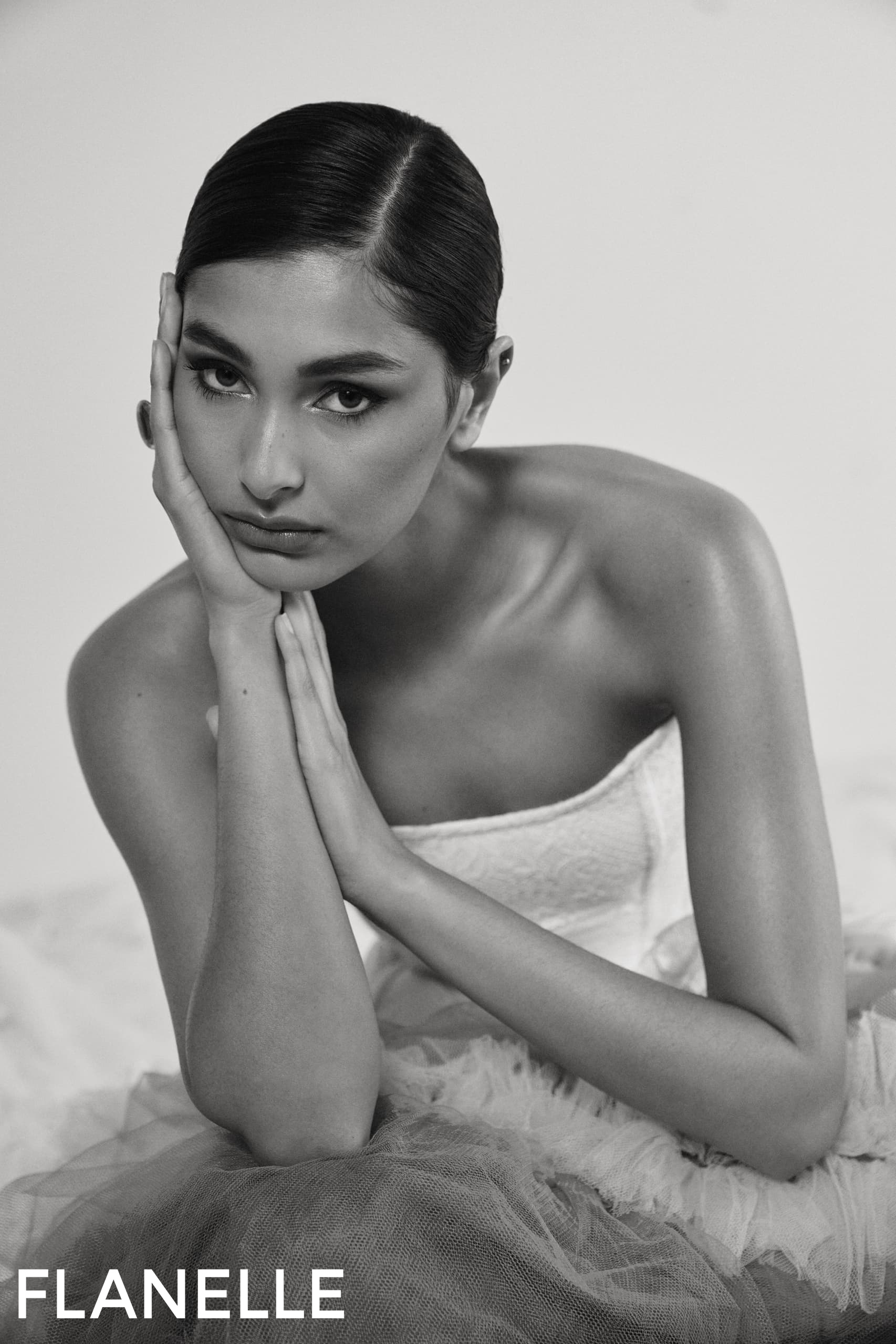 Elegant woman in black and white, wearing a strapless dress, thoughtful pose.