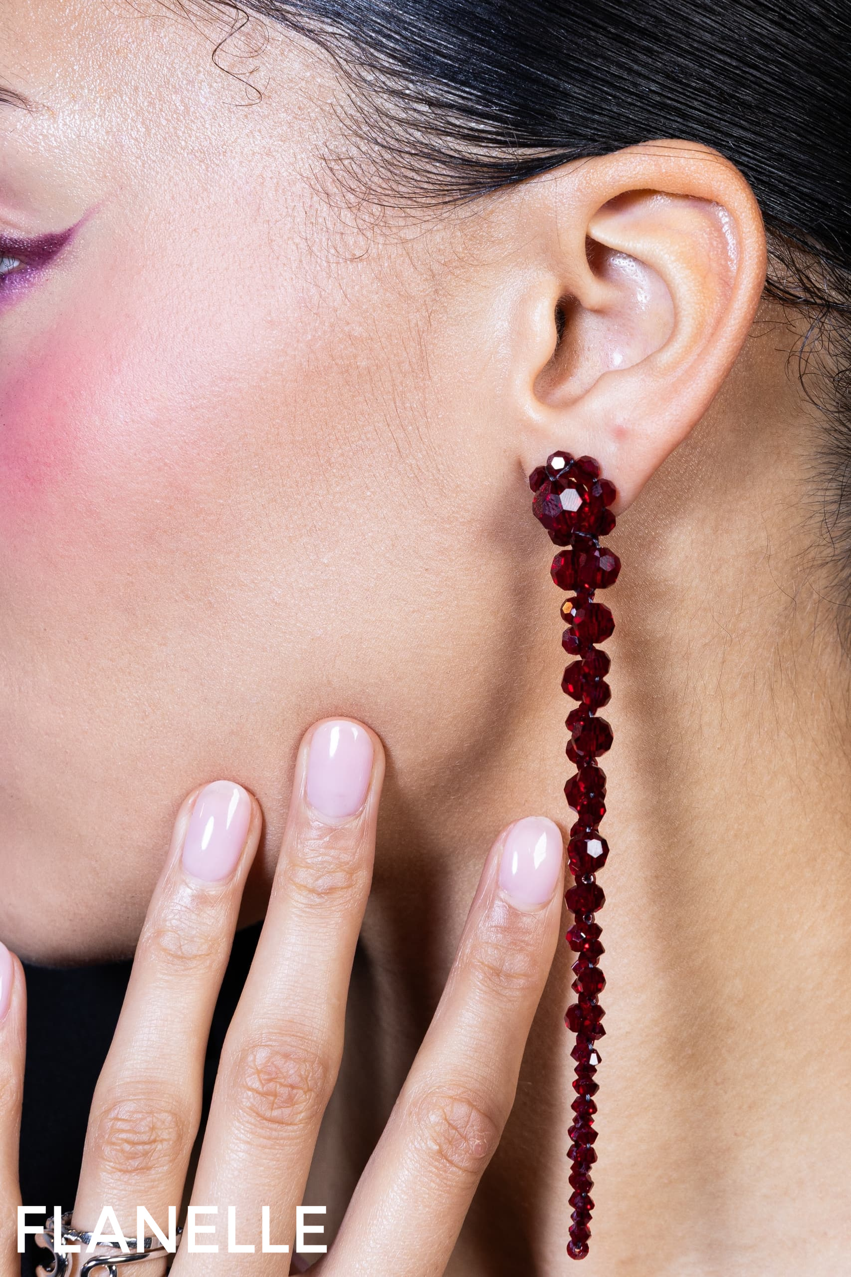 Elegant long red earrings showcased on model with polished nails.