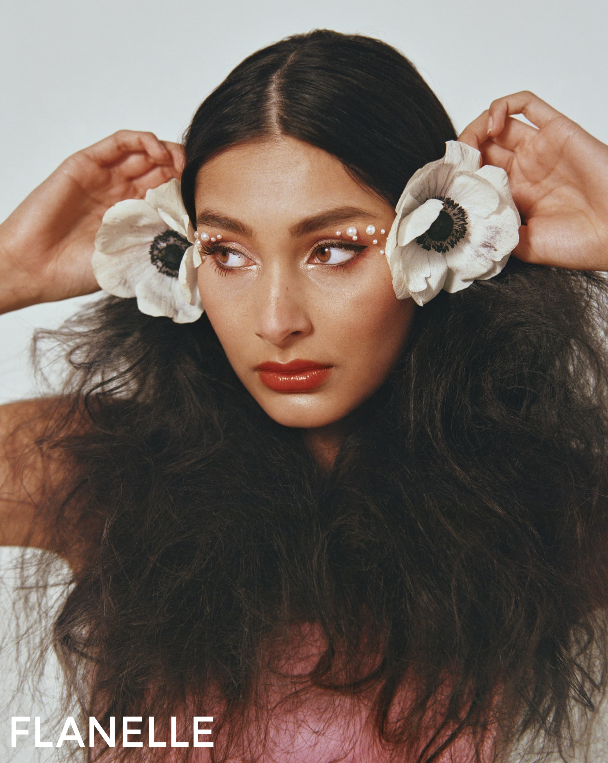 Elegant woman with floral hairpieces and creative makeup.