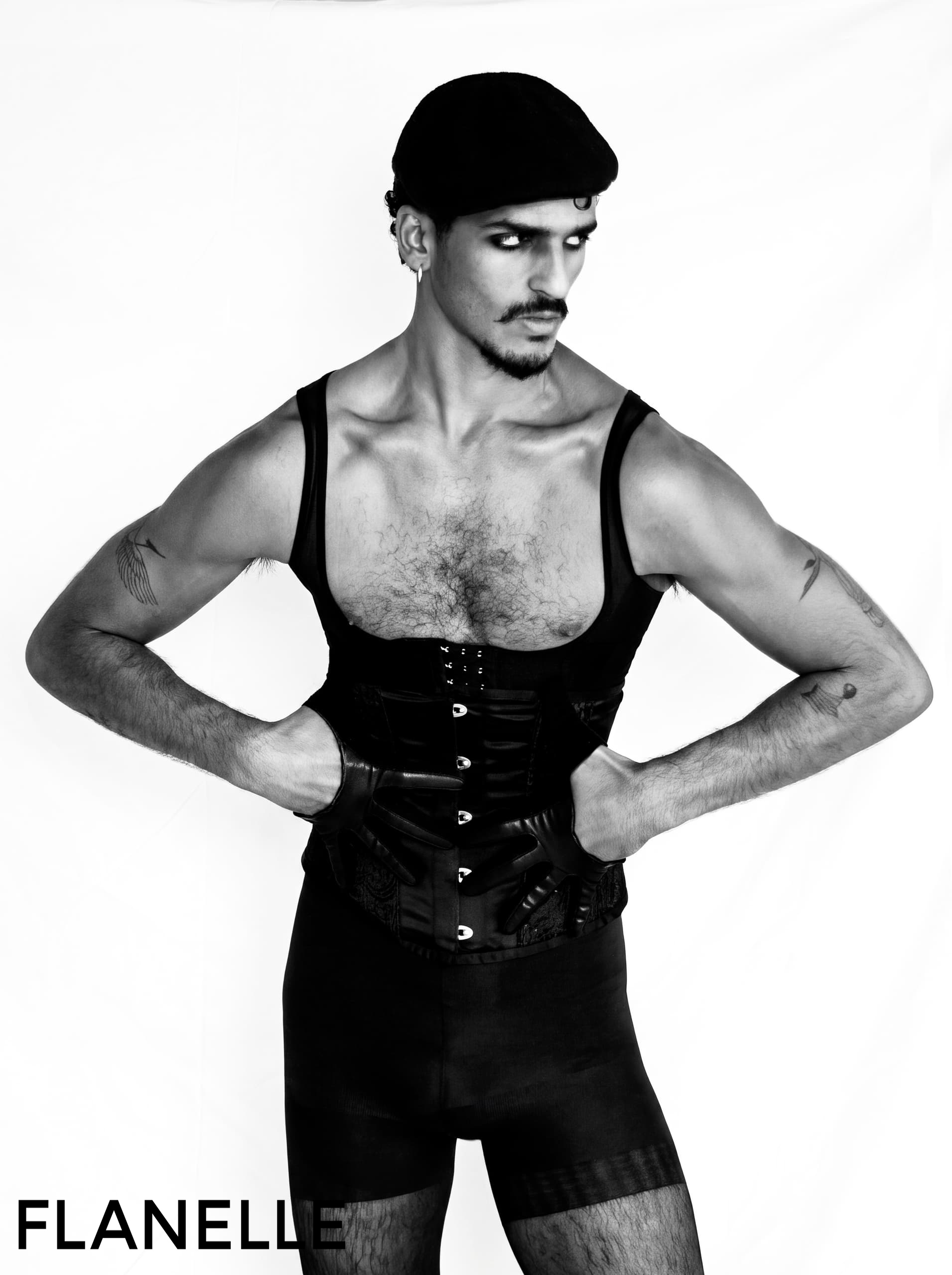 Male model poses in stylish black outfit and cap, Flanelle magazine photoshoot.