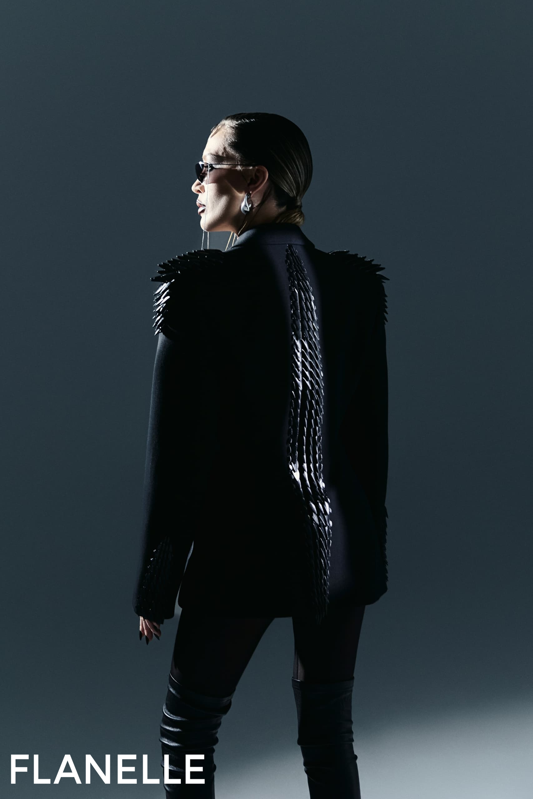 Fashionable woman in designer jacket and sunglasses, dramatic lighting.