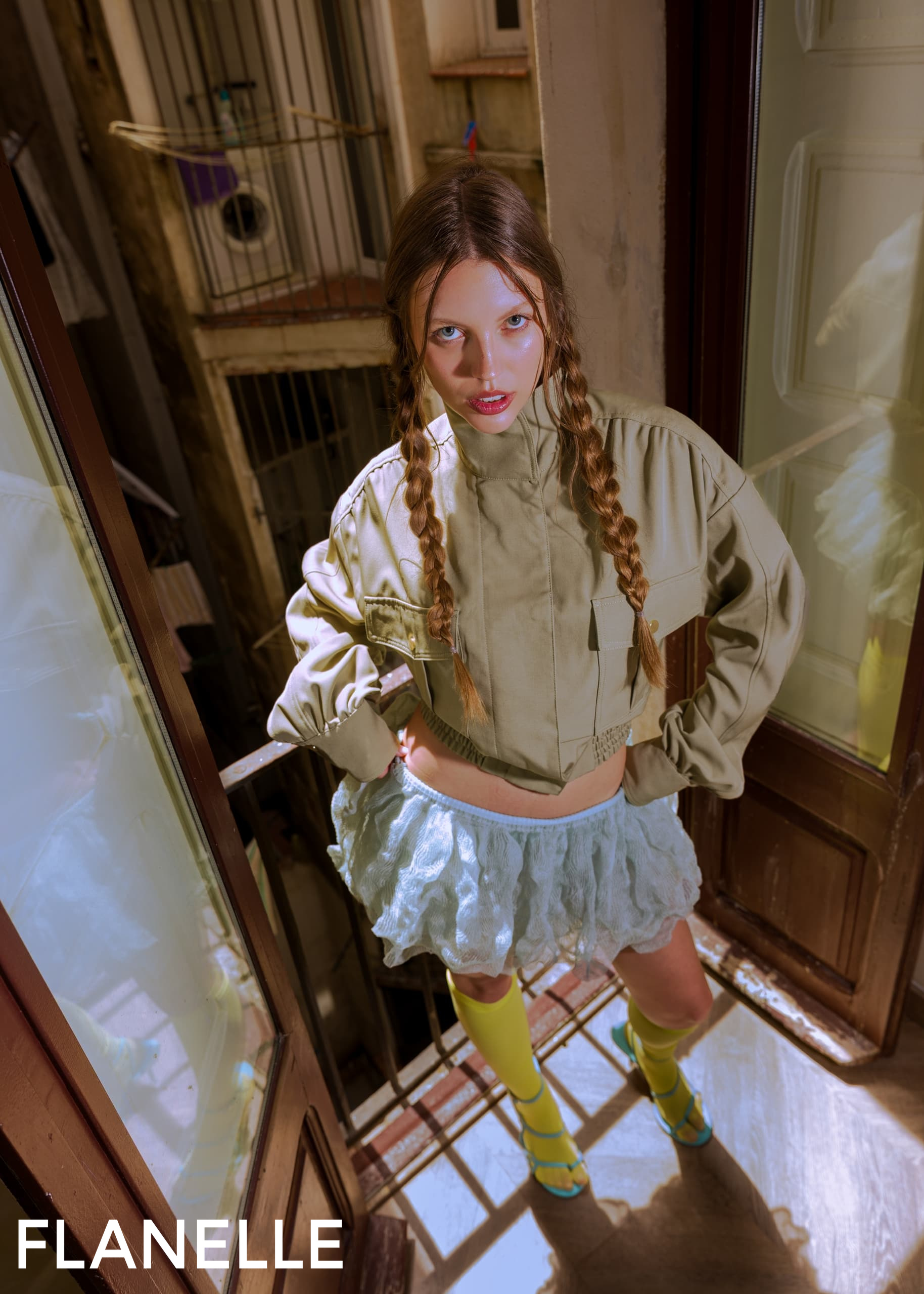 Fashionable woman in urban setting wearing unique outfit with braids and bold colors.