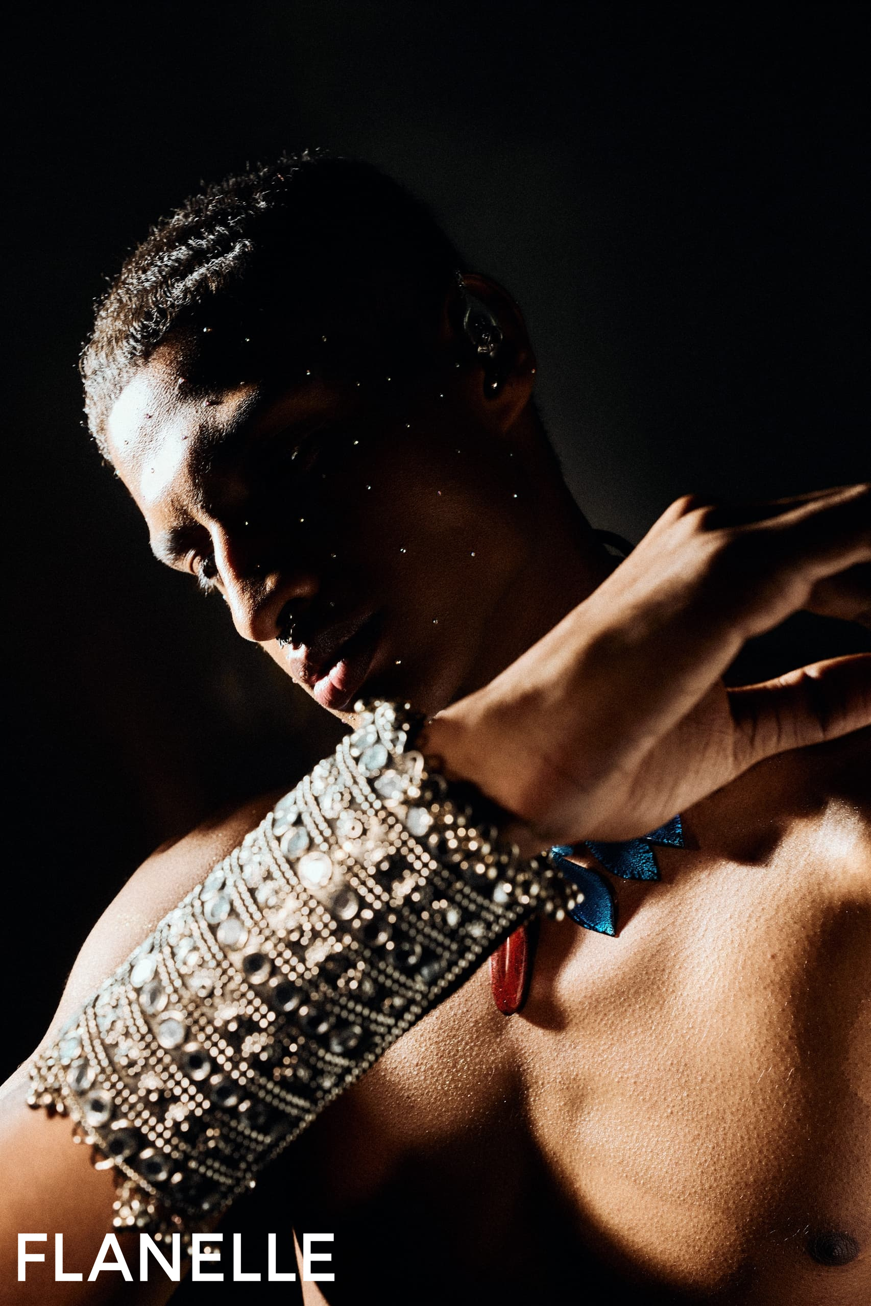 Fashion model with elaborate arm jewelry and creative lighting.