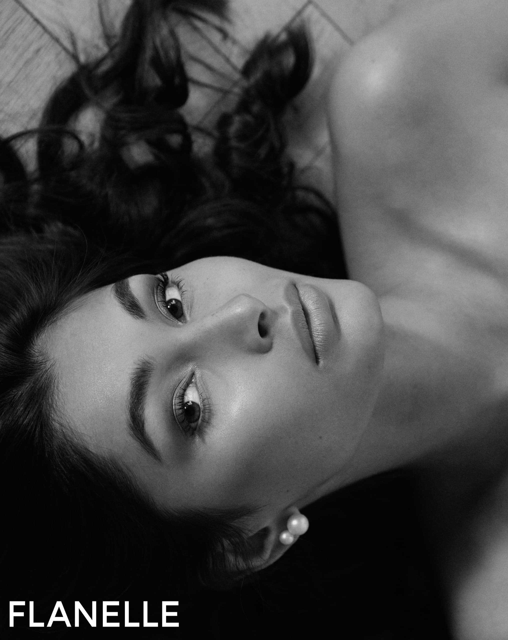 Elegant woman lying down, black and white portrait with Flanelle text.