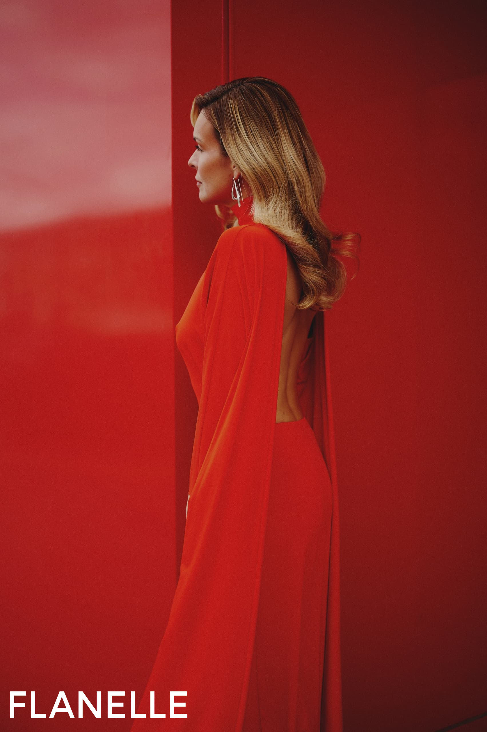 Woman in red elegant dress with waves against a matching red background.