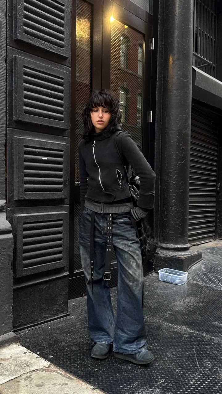 Person wearing dark streetwear fashion, urban backdrop.