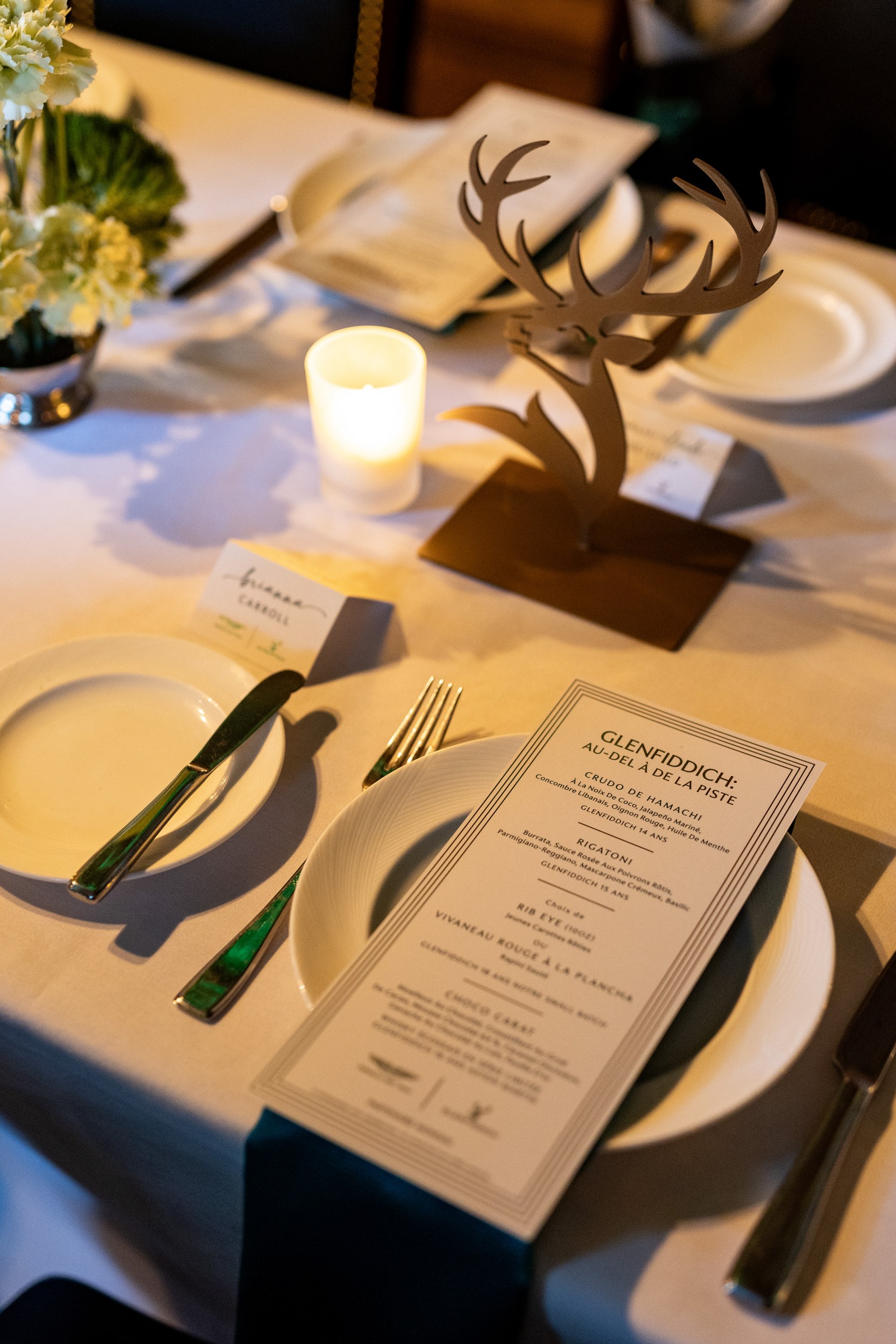 Elegant dinner setup with menu, candle, and deer antler centerpiece.