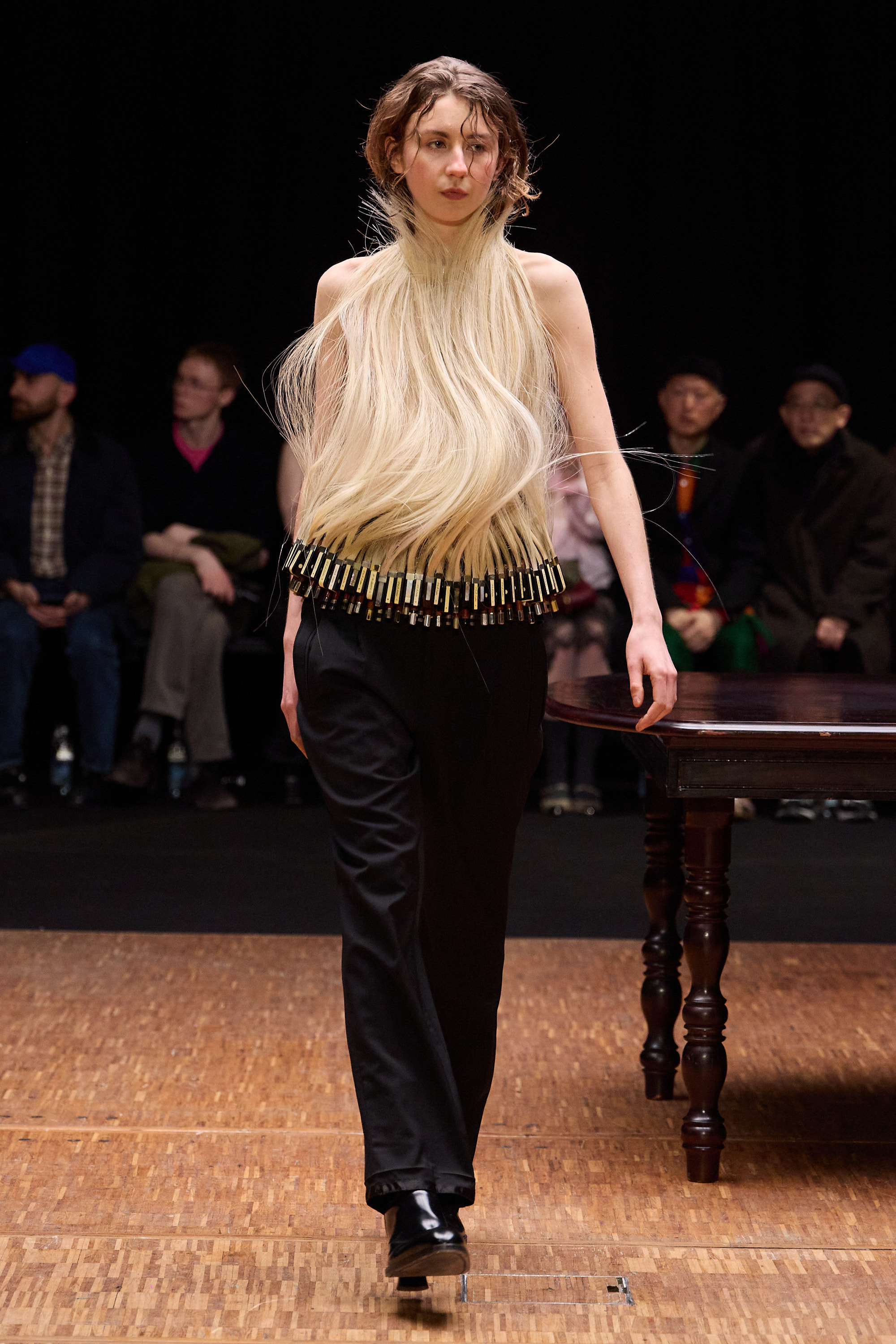Model in avant-garde outfit with long, flowing hair on a fashion runway.
