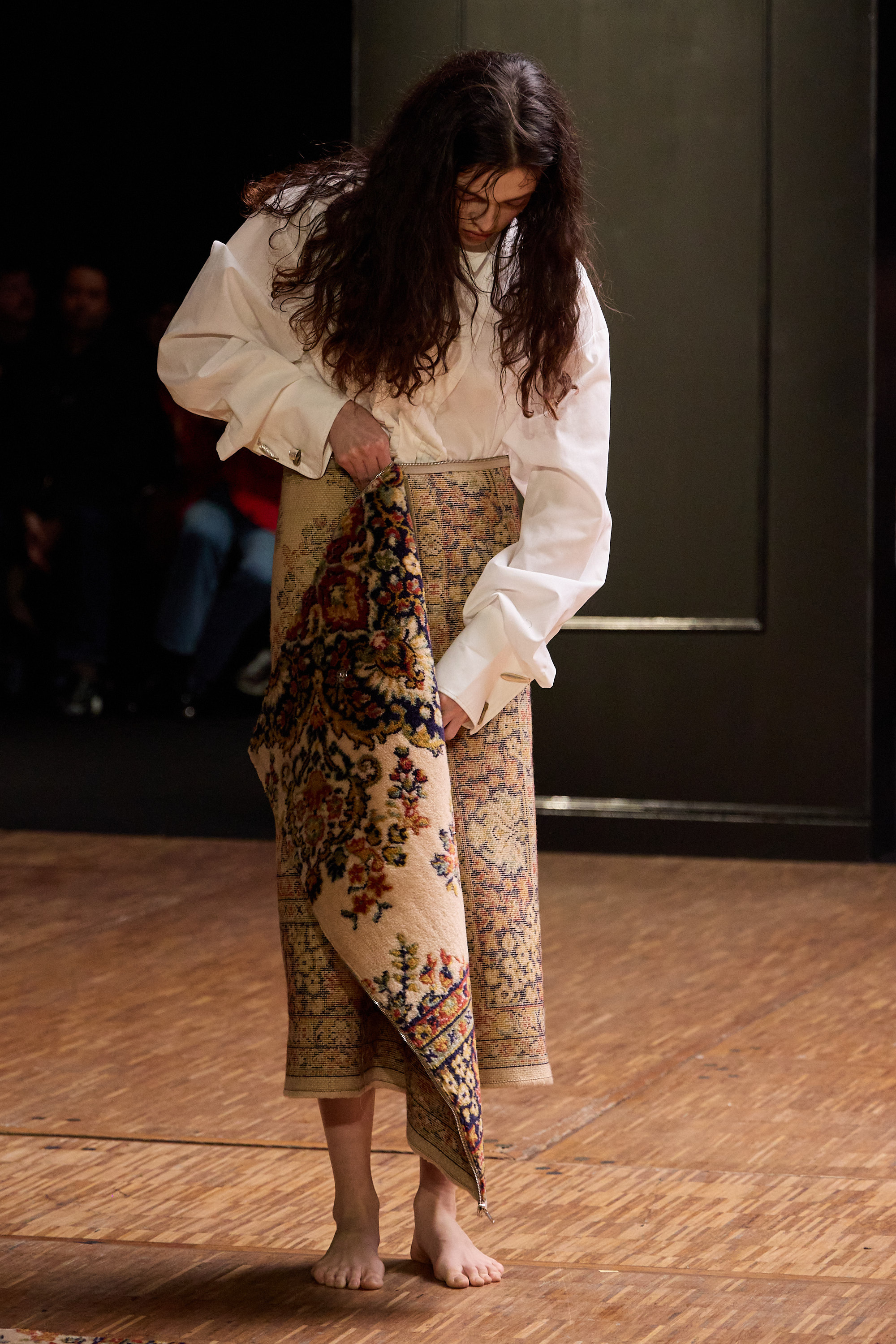Fashion model wearing a unique carpet-inspired dress on the runway.