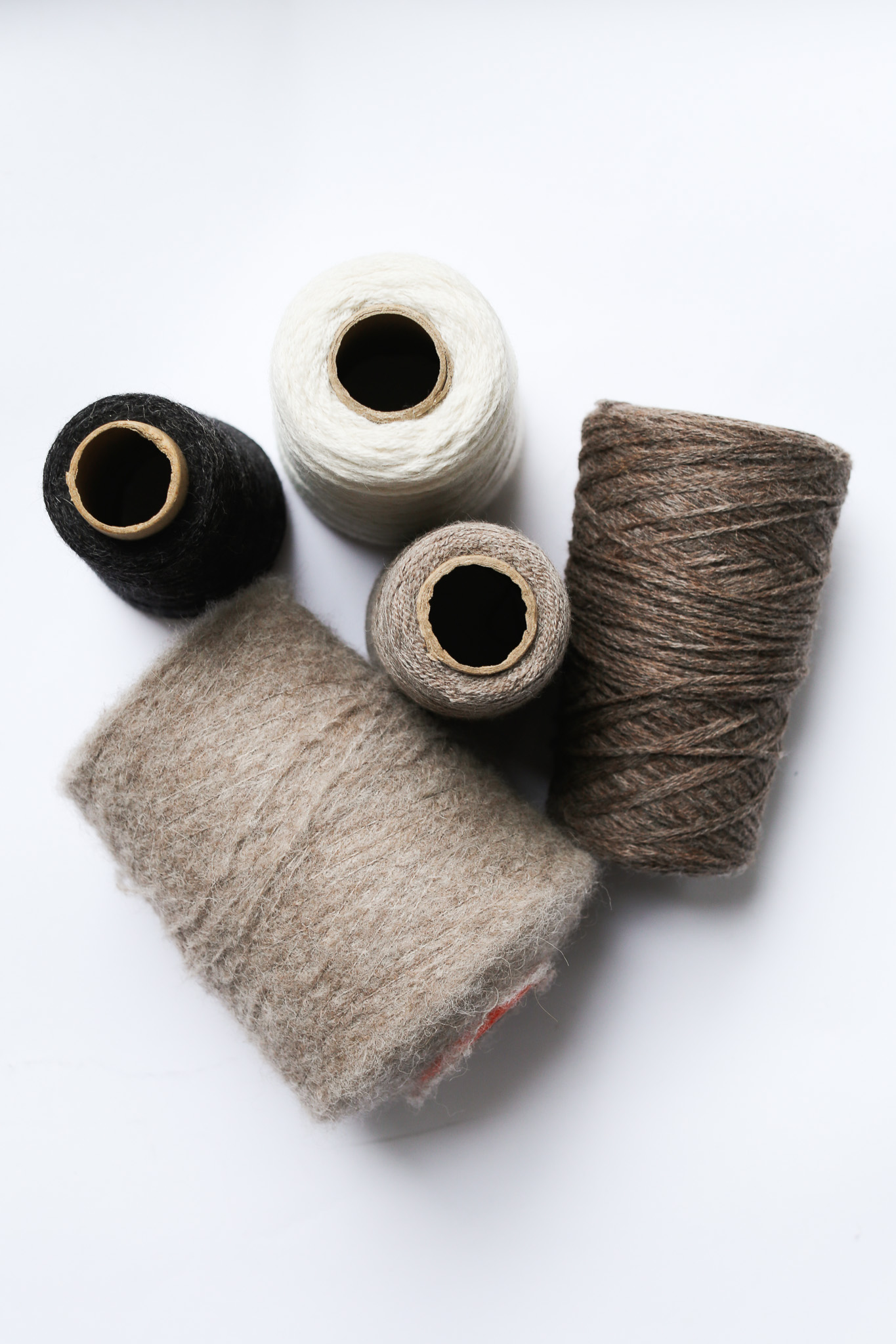 Various spools of colorful yarn on a white background.