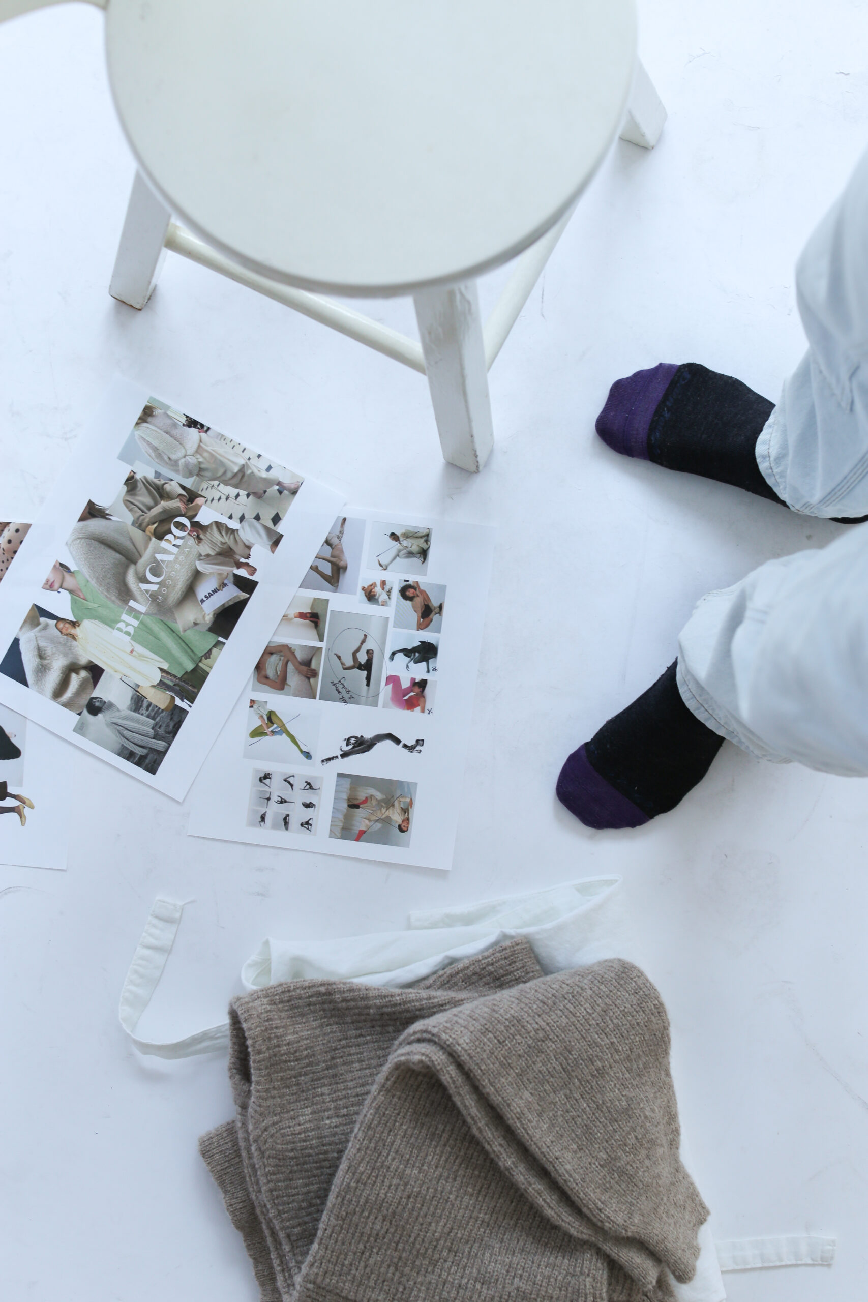 Cozy socks by a chair with fashion magazines and a warm sweater on the floor.