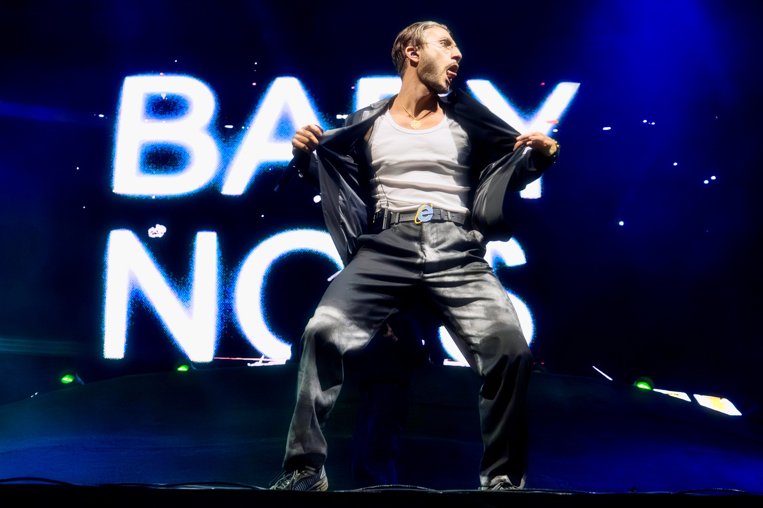 Performer in spotlight on stage with illuminated background text.