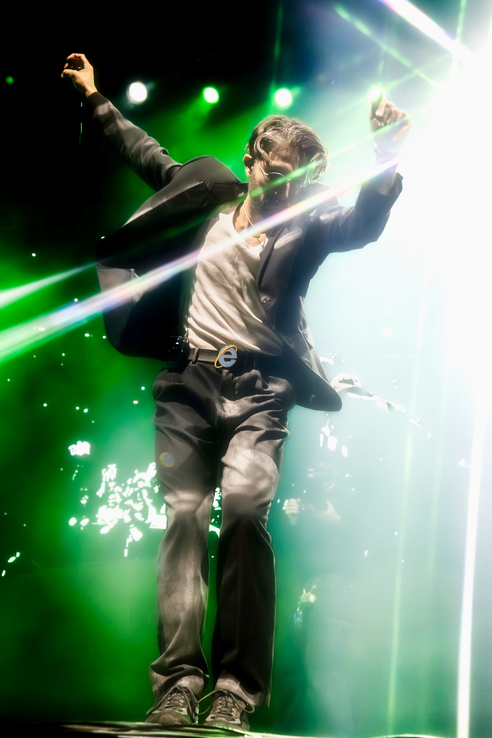 Performer dancing energetically on stage with vibrant green lights.