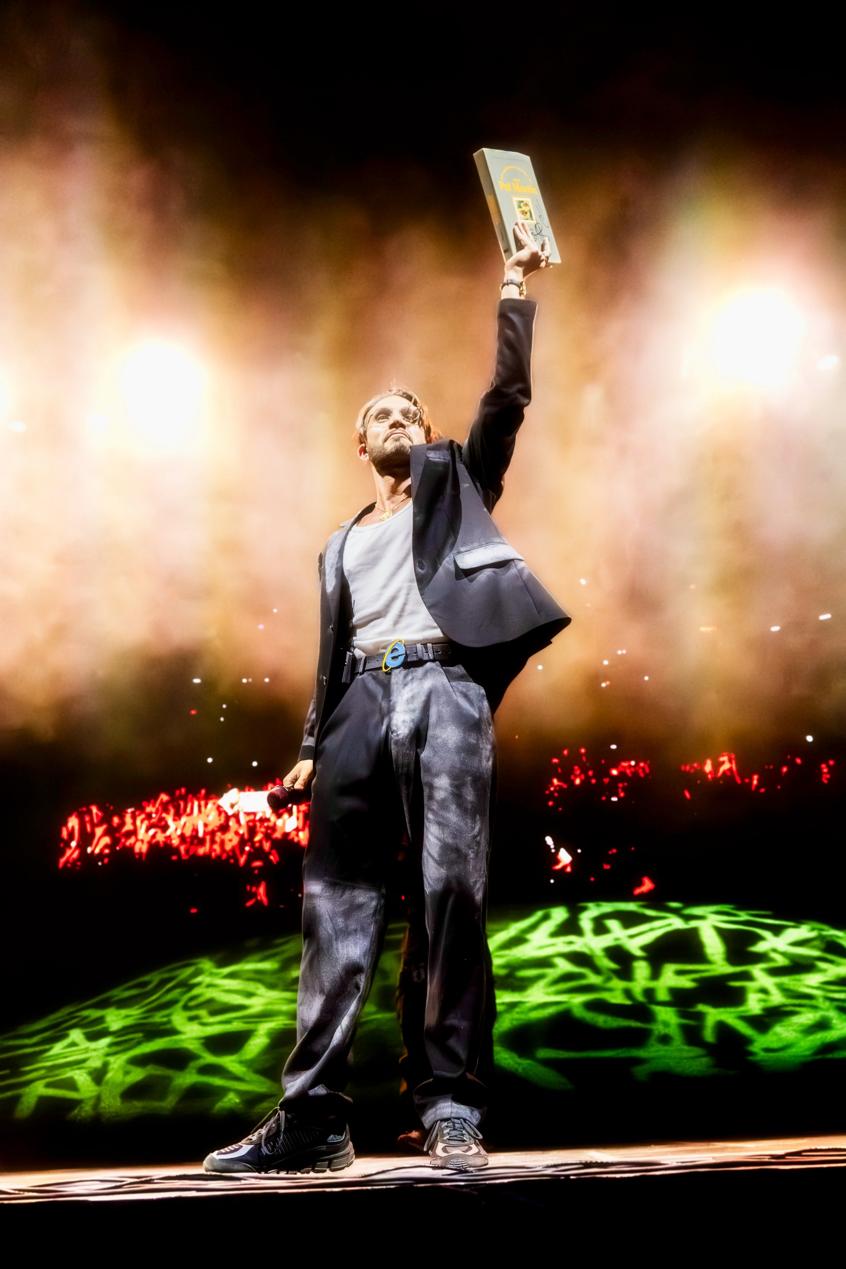 Performer triumphantly holding award on stage with vibrant lighting effects.