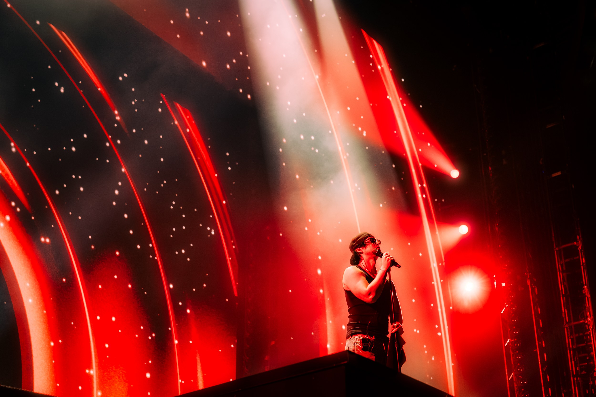 Singer on stage with dynamic red and white lights during a live concert performance.