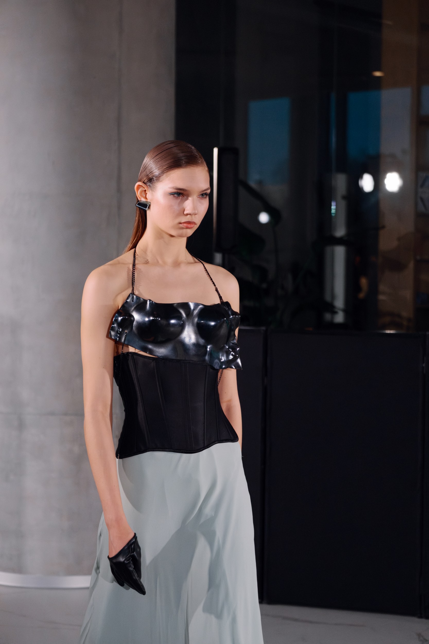 Fashion model in avant-garde black corset dress on runway.