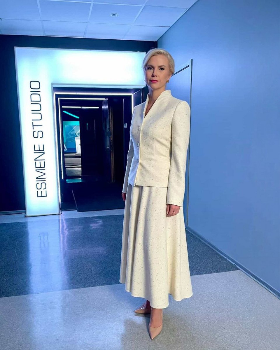 Person in elegant white outfit stands in bright studio hallway.