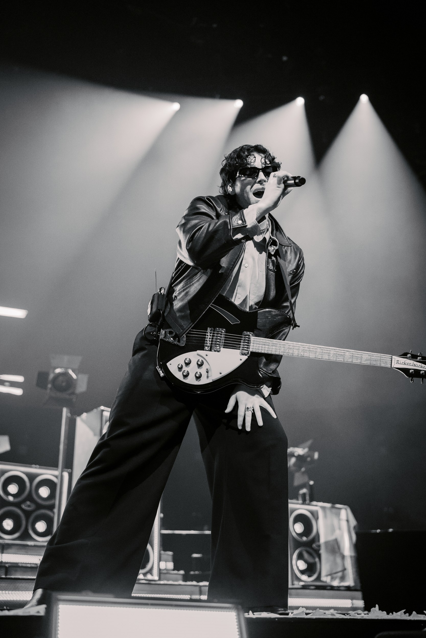 Rock singer performing on stage with guitar, dramatic lighting in black and white.