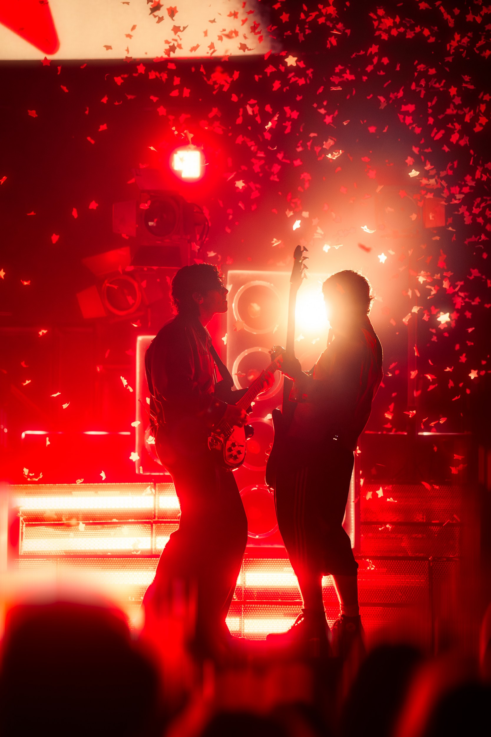 Silhouetted musicians on stage with red lights and confetti.