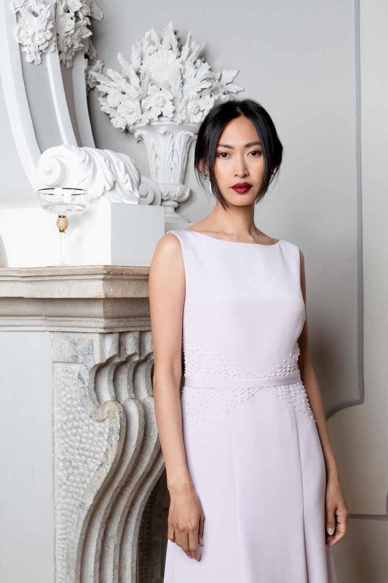 Woman in elegant evening gown beside ornate fireplace.
