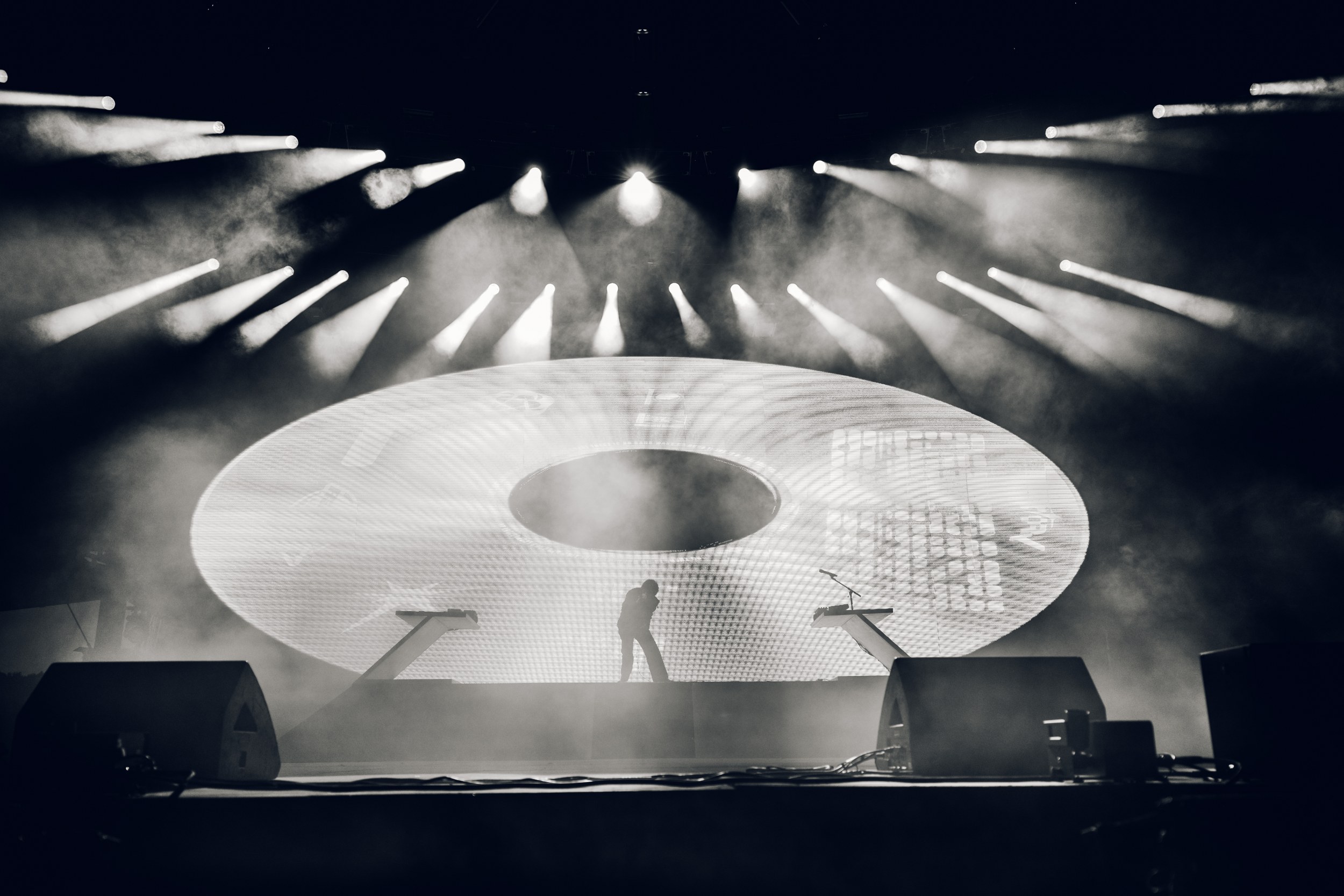 Concert stage with dramatic lighting and a large circular screen display.